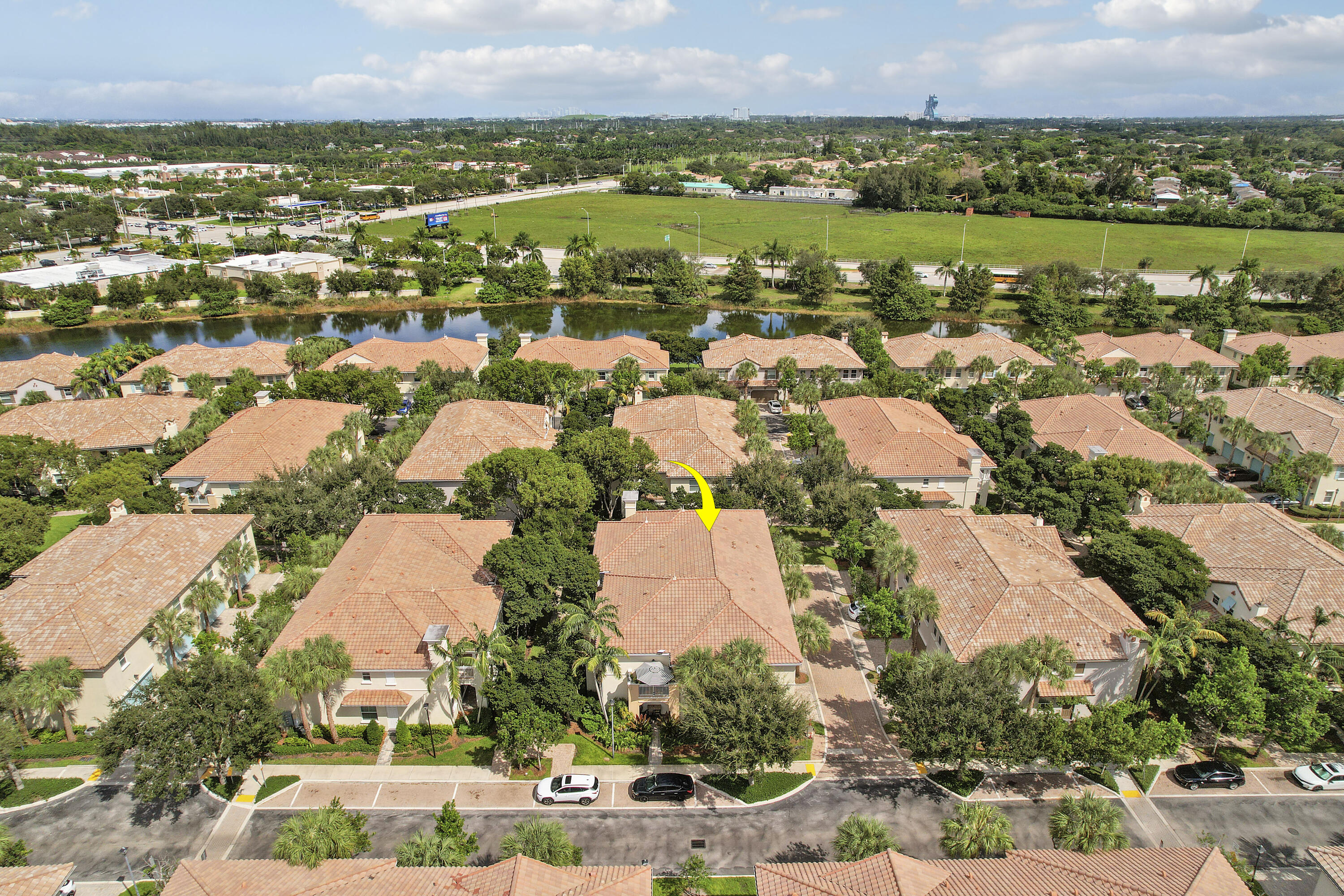 Aerial perspective of a multi-unit residential property featuring terra cotta tile roofing, mature landscaping, and an attached driveway Aerial perspective of a multi-unit residential property featuring terra cotta tile roofing, mature landscaping, and an attached driveway