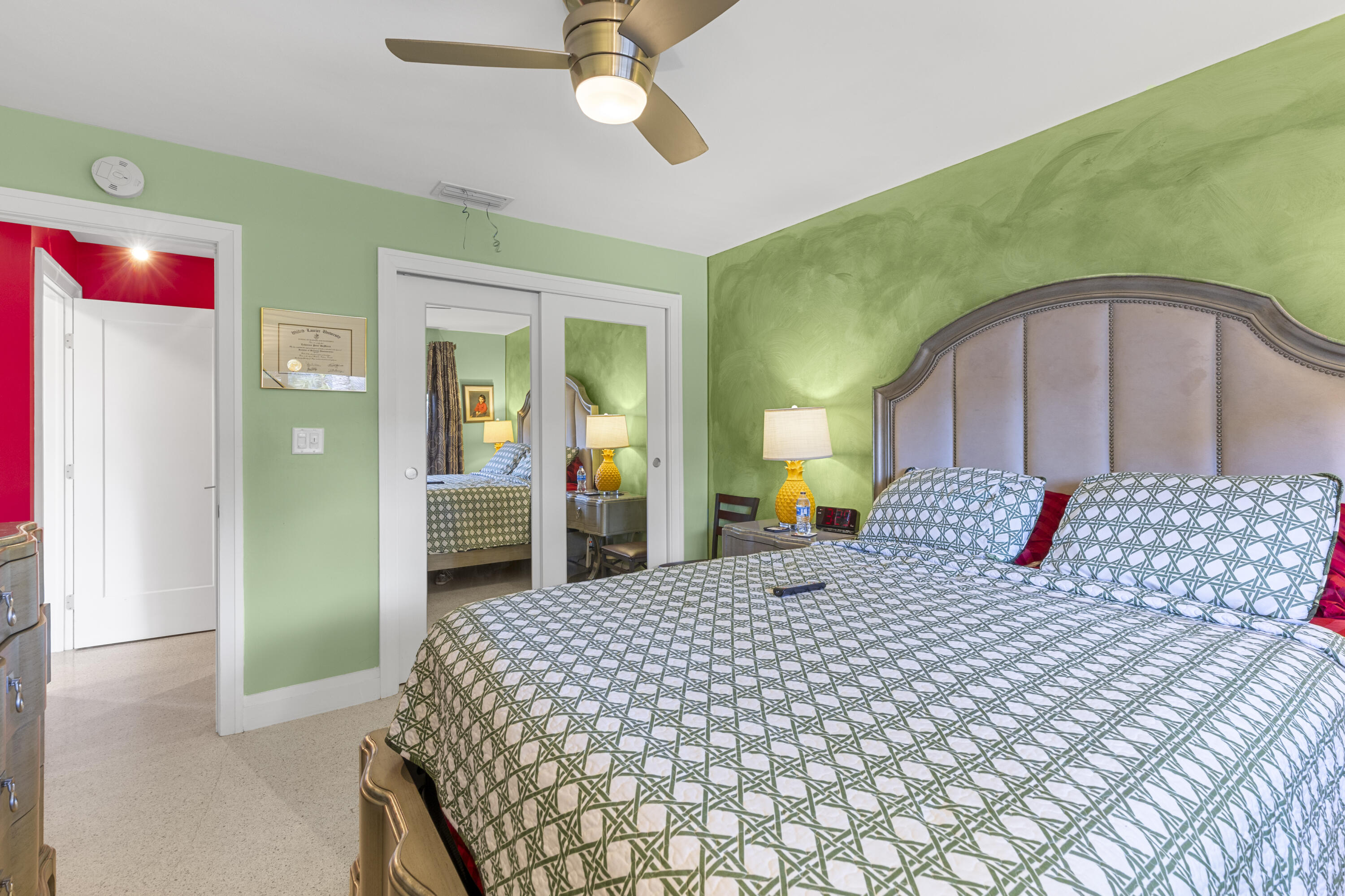 Room featuring a brushed-finish metal ceiling fan with integrated lighting, dual sliding mirrored closet doors, and solid-core interior doors