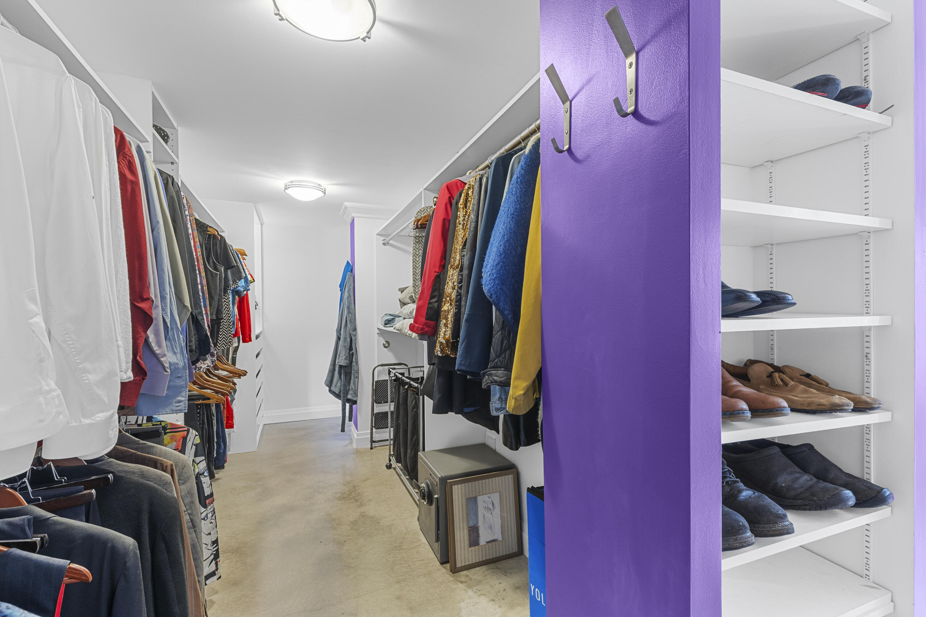 Walk-in closet featuring extensive built-in shelving, adjustable hanging rods, flush-mount ceiling lighting, and wall-mounted storage hooks