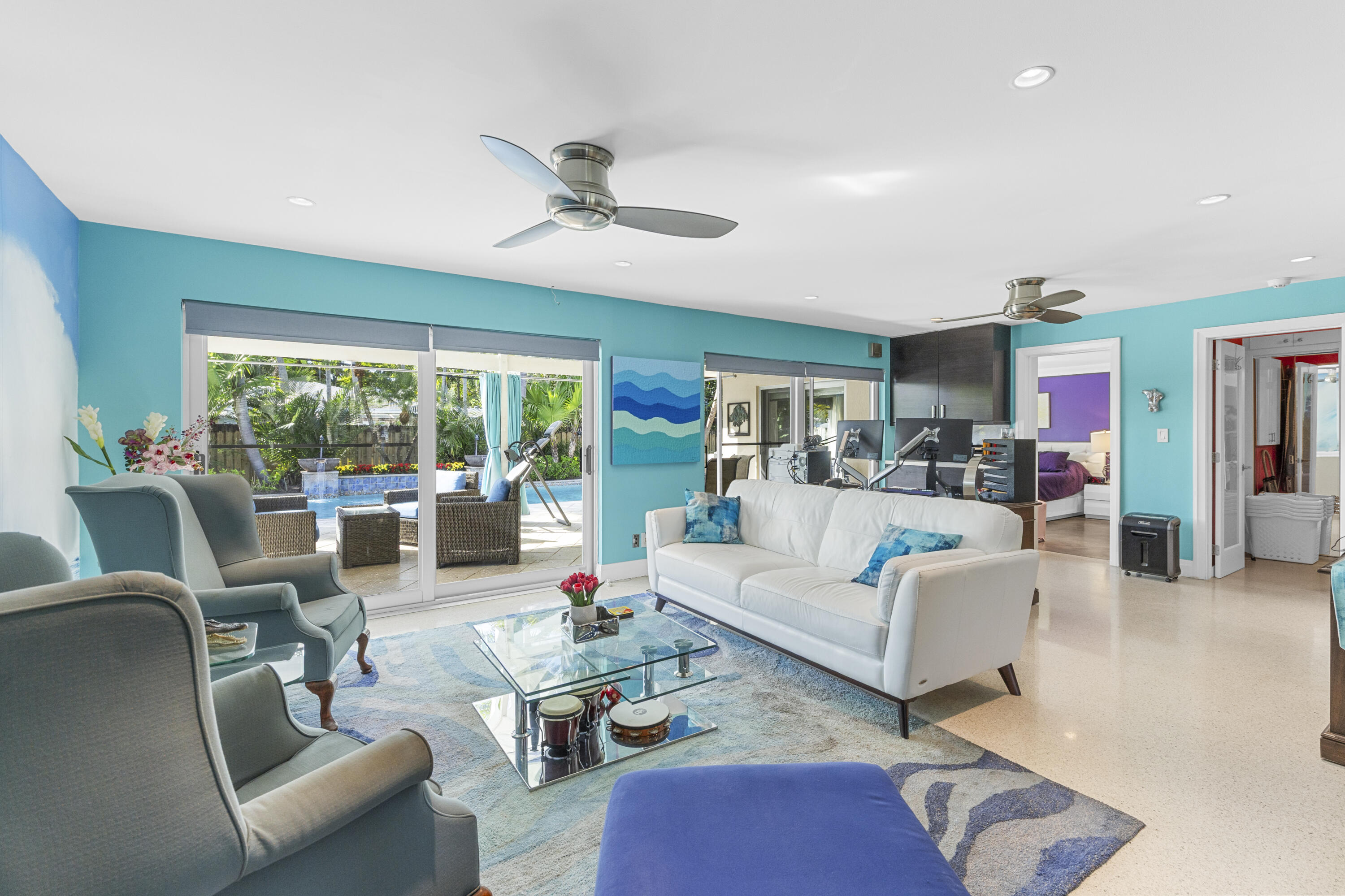 Living area featuring sliding glass doors, recessed lighting, ceiling fans, and polished stone flooring