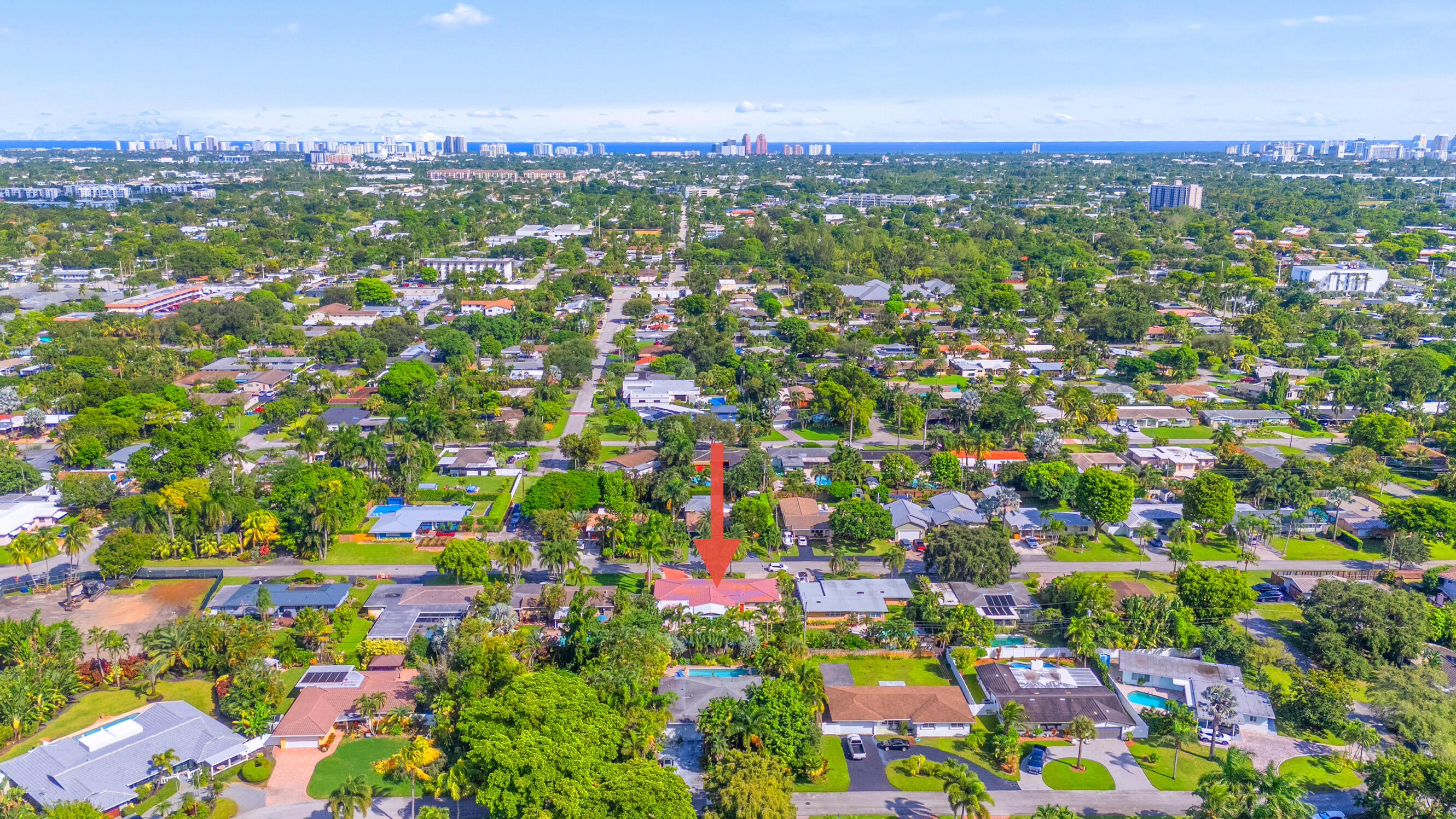 Aerial perspective of property featuring a pitched roof, attached garage, private swimming pool, and dense perimeter landscaping