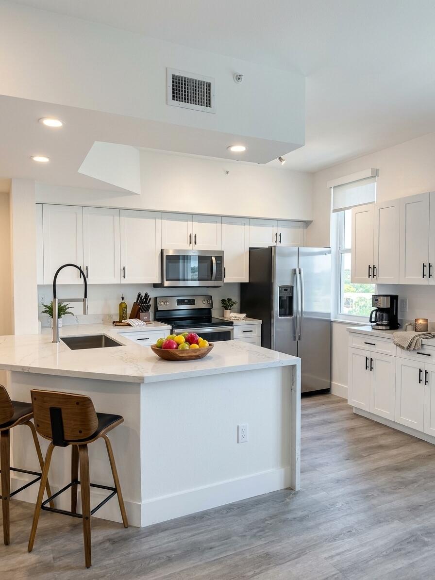 Kitchen featuring white shaker-style cabinetry, quartz countertops, a central island with a high-arch faucet, stainless steel appliances, and wood-finish flooring Kitchen featuring white shaker-style cabinetry, quartz countertops, a central island with a high-arch faucet, stainless steel appliances, and wood-finish flooring