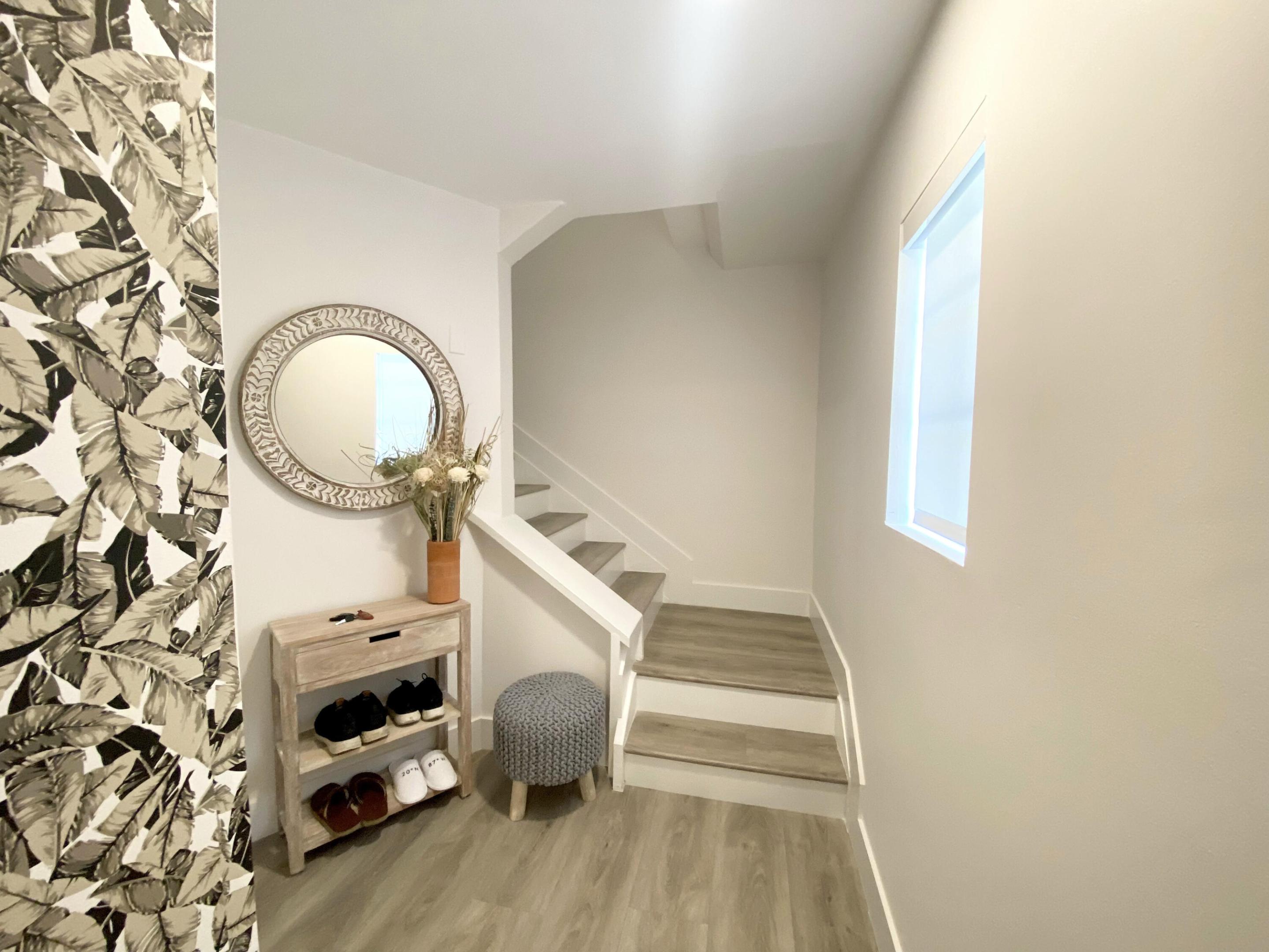 Foyer featuring patterned wall covering, wood-finish flooring, a rectangular window, and a staircase with wood-finish treads