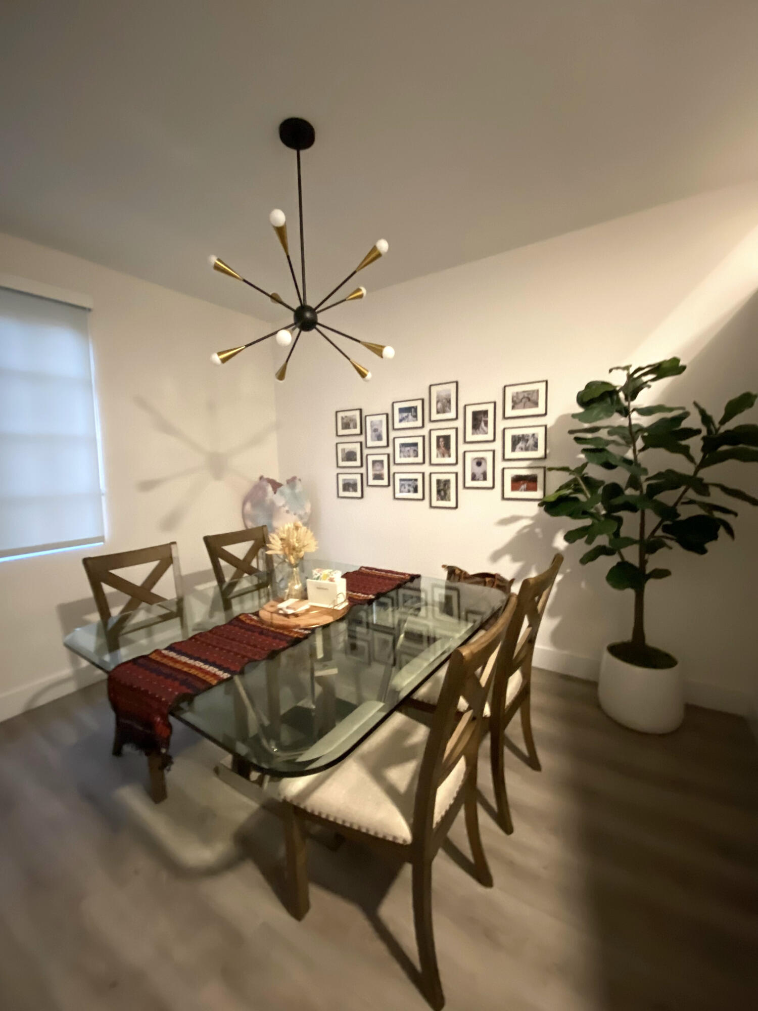 Modern sputnik-style chandelier with a matte black and metallic finish, paired with wood-finish flooring and a neutral color palette