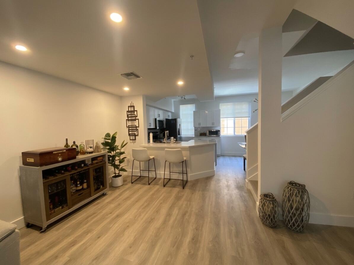 Open-concept interior featuring wood-finish flooring, recessed lighting, white cabinetry, and a peninsula with a countertop Open-concept interior featuring wood-finish flooring, recessed lighting, white cabinetry, and a peninsula with a countertop