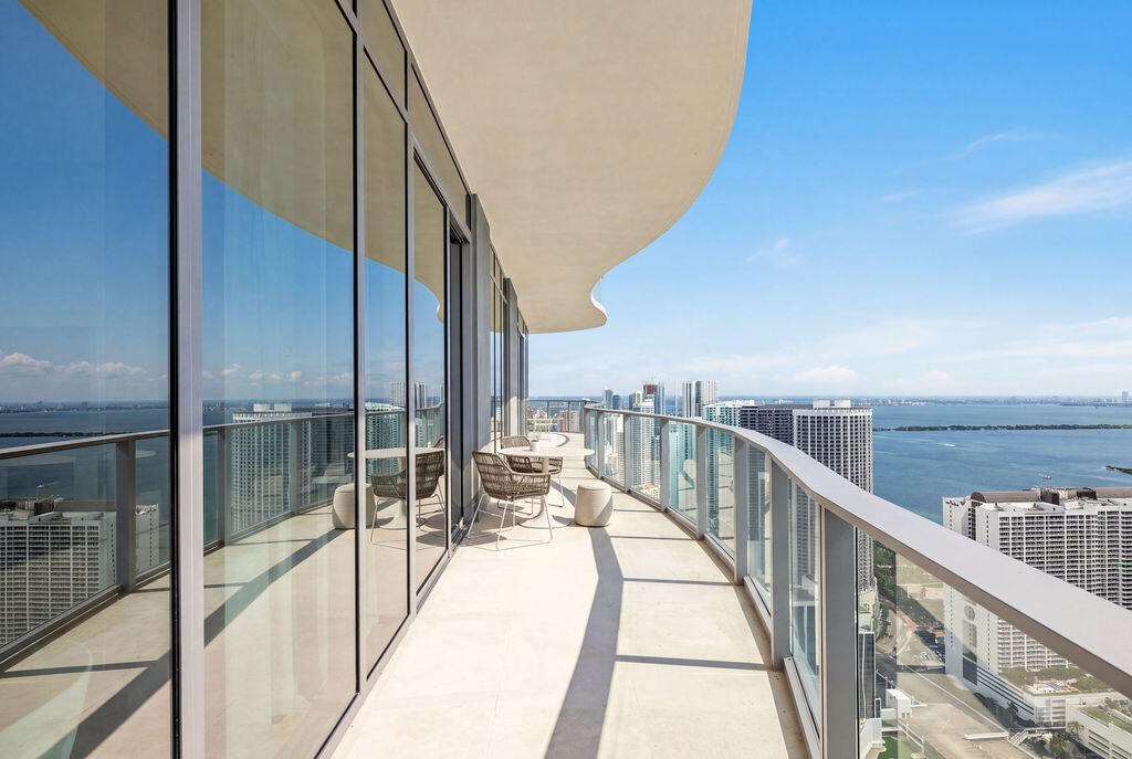 Expansive curved balcony featuring floor-to-ceiling glass paneling, tile flooring, and a sleek metal railing