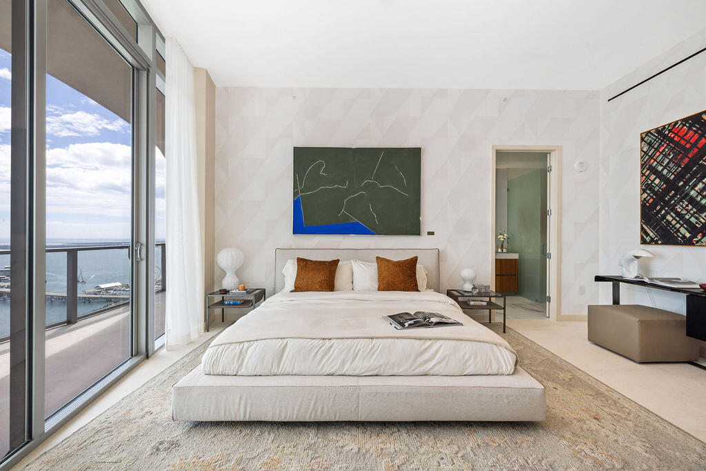 Floor-to-ceiling glass sliding doors, private balcony with metal railing, textured patterned wall treatment, and smooth-finish flooring