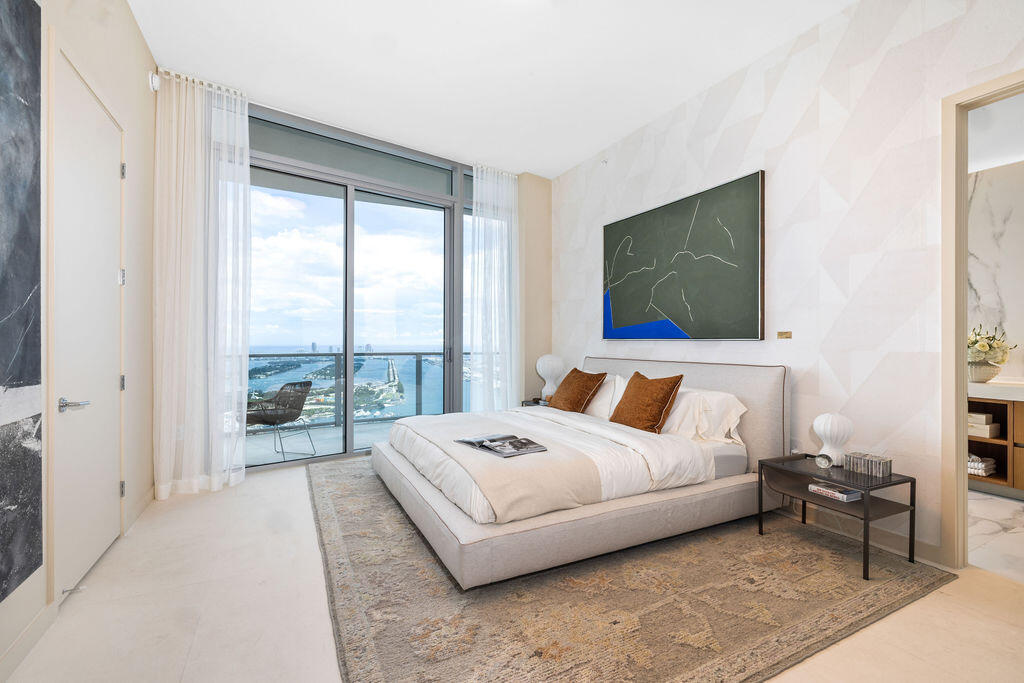 Floor-to-ceiling glass sliding doors opening to a private balcony, textured wall paneling, and stone flooring