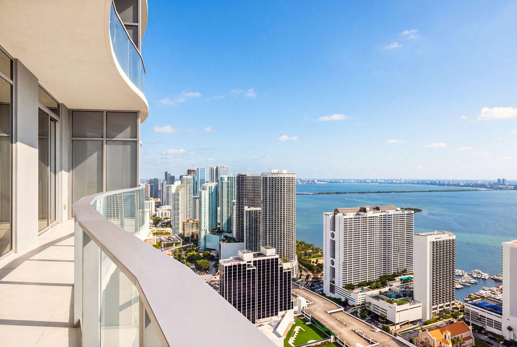 Curved balcony featuring floor-to-ceiling glass panel railing and oversized light-toned tile flooring