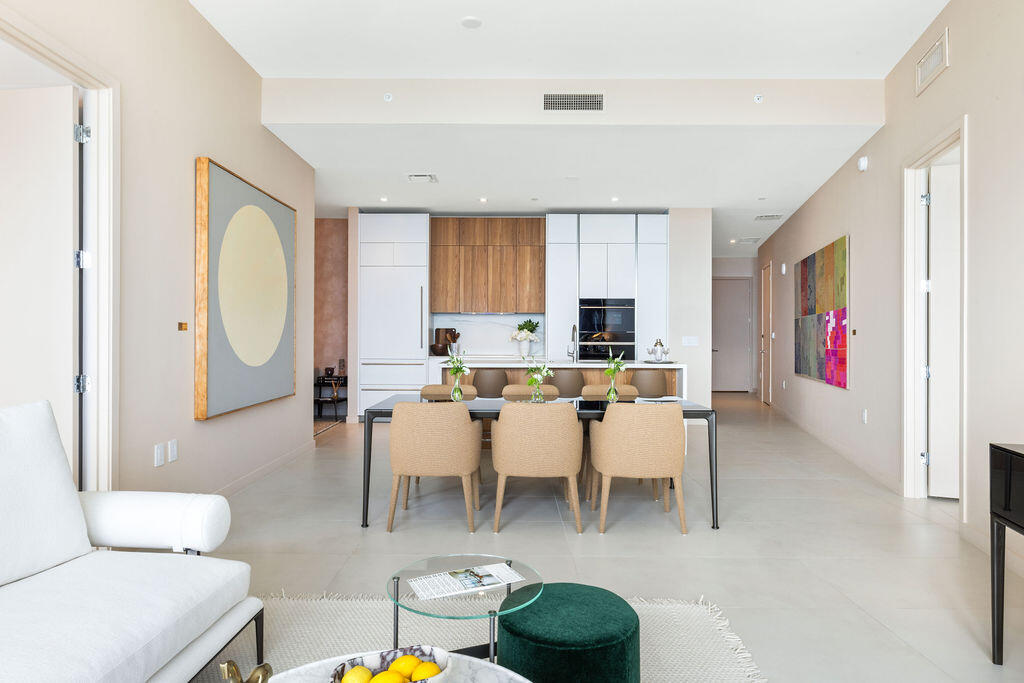 Open-concept kitchen featuring custom wood-finish and matte white cabinetry, integrated appliances, and a central island with a stone-finish countertop