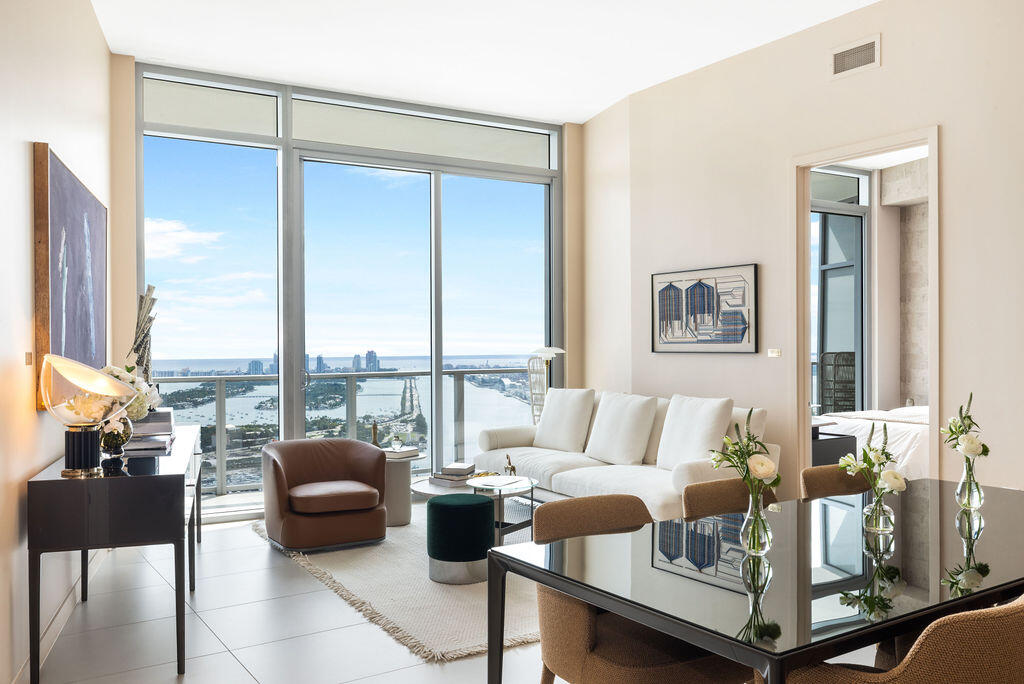 Floor-to-ceiling windows featuring panoramic water and city skyline outlooks, large-format tile flooring, and glass balcony railings