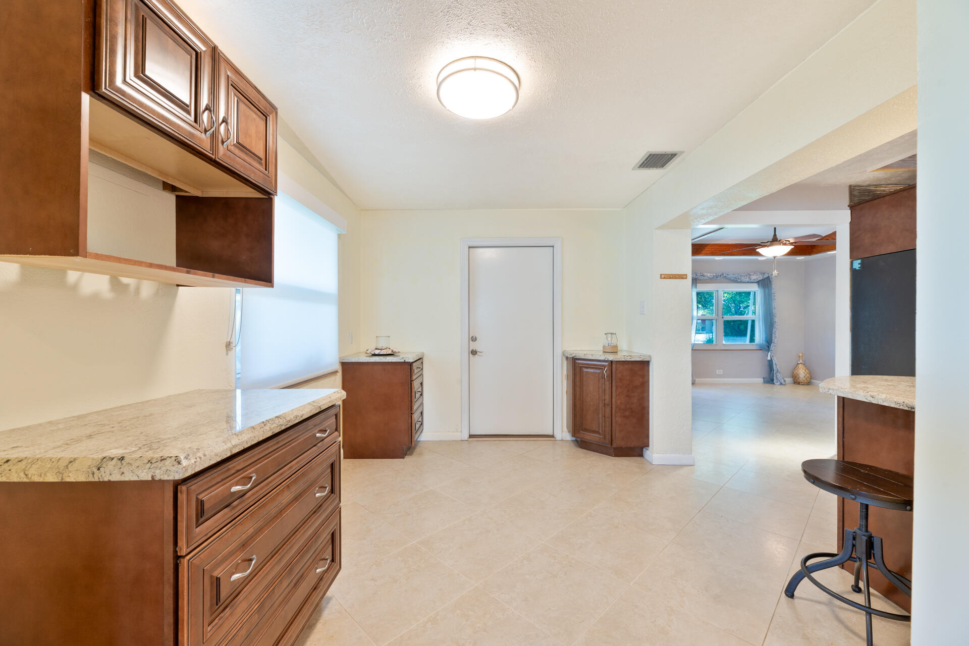 Dining area featuring wood cabinetry, stone-finish countertops, tile flooring, and a flush-mount ceiling light fixture