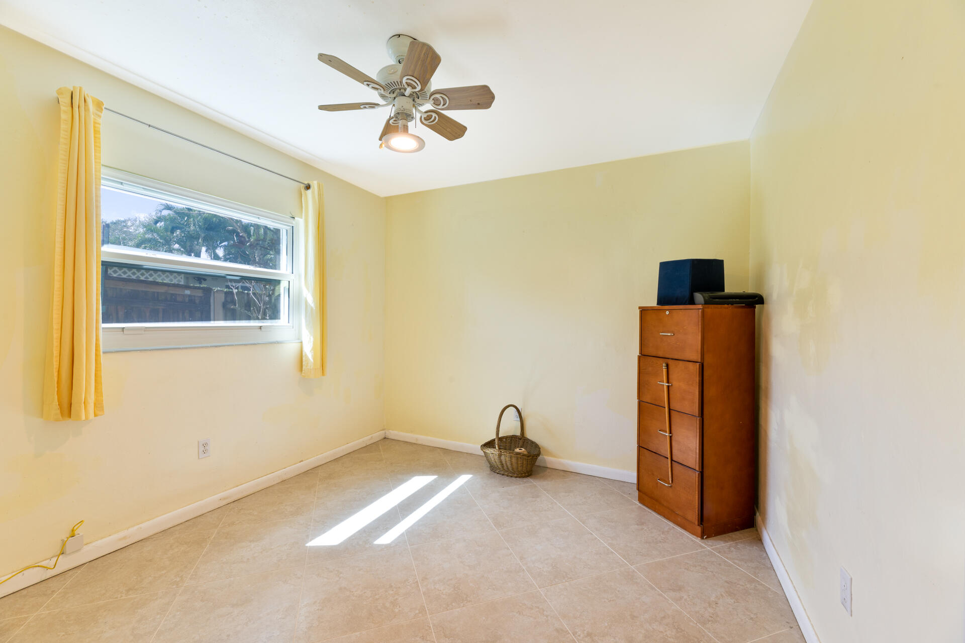 Neutral-toned tile flooring, light-colored walls, multi-pane window, and ceiling fan with integrated light fixture