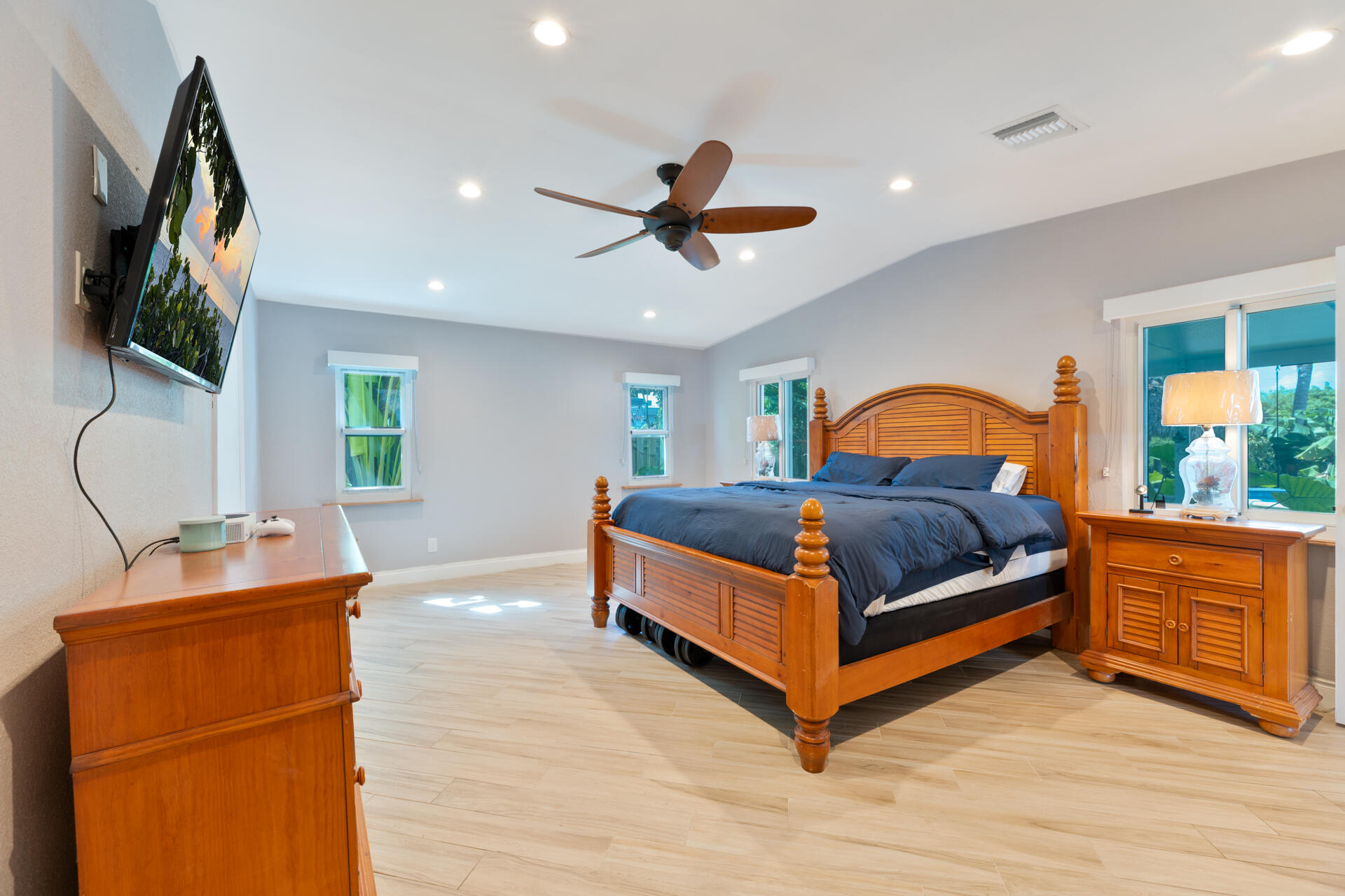 Vaulted ceilings featuring recessed lighting and a ceiling fan, complemented by ceramic plank flooring and multiple windows