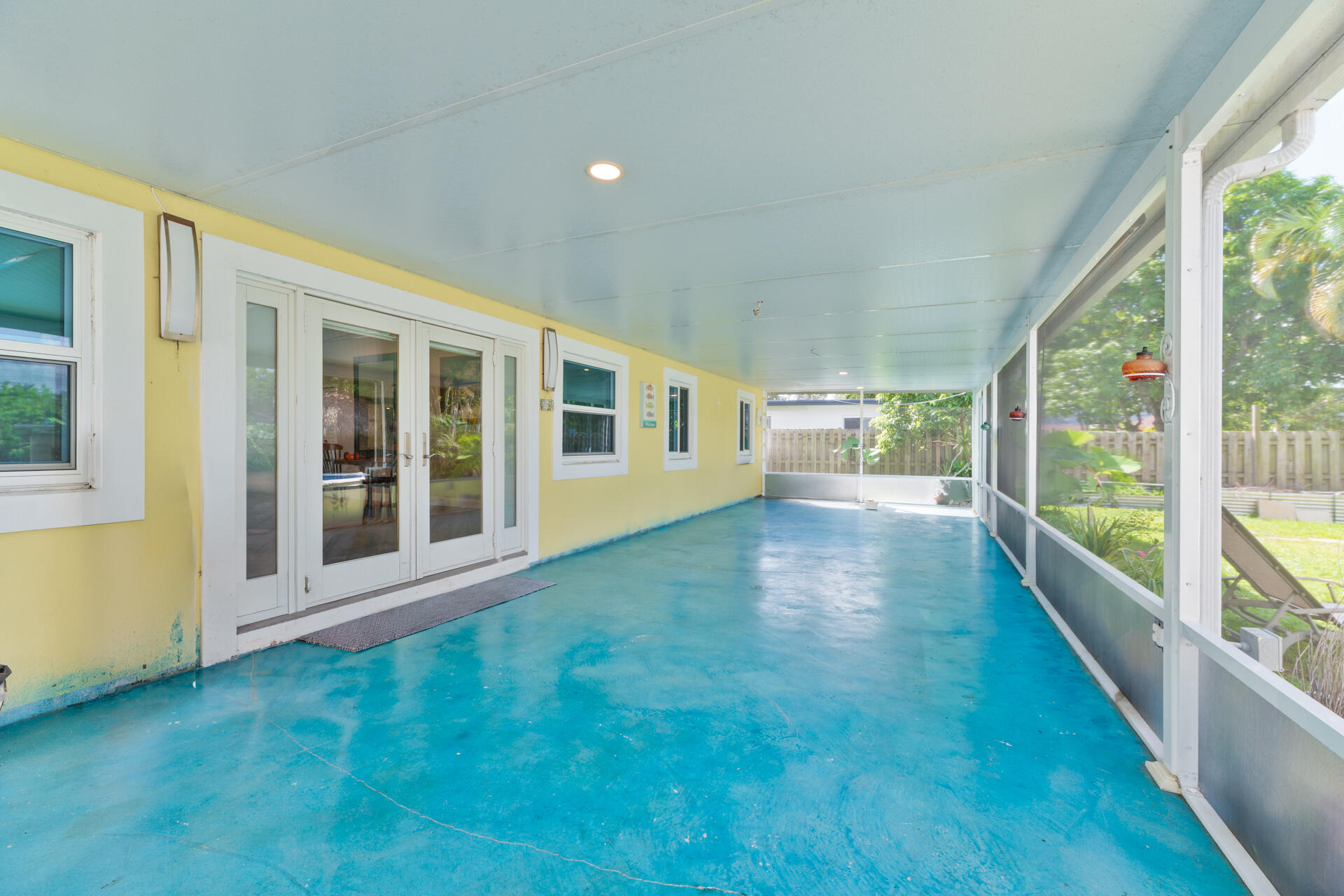 Screened-in porch featuring a painted concrete floor, recessed lighting, and double-door entry with sidelights