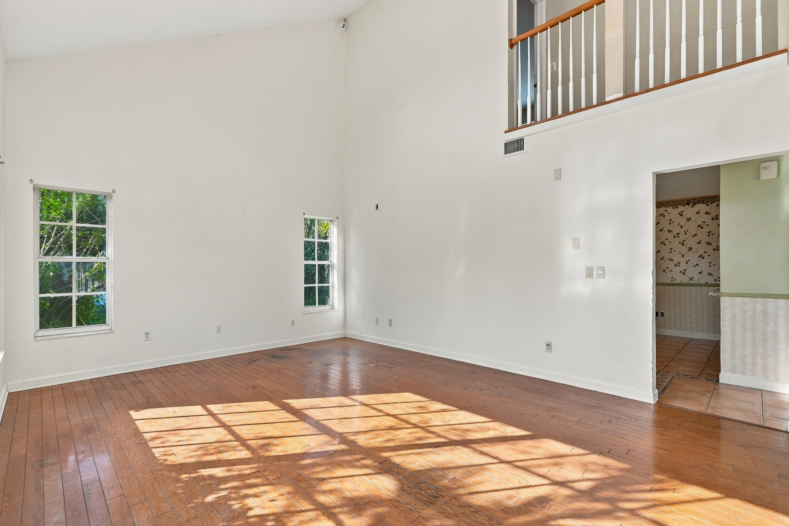 Vaulted ceilings, wood-finish flooring, multi-pane windows, and a railed mezzanine overlooking the open interior space