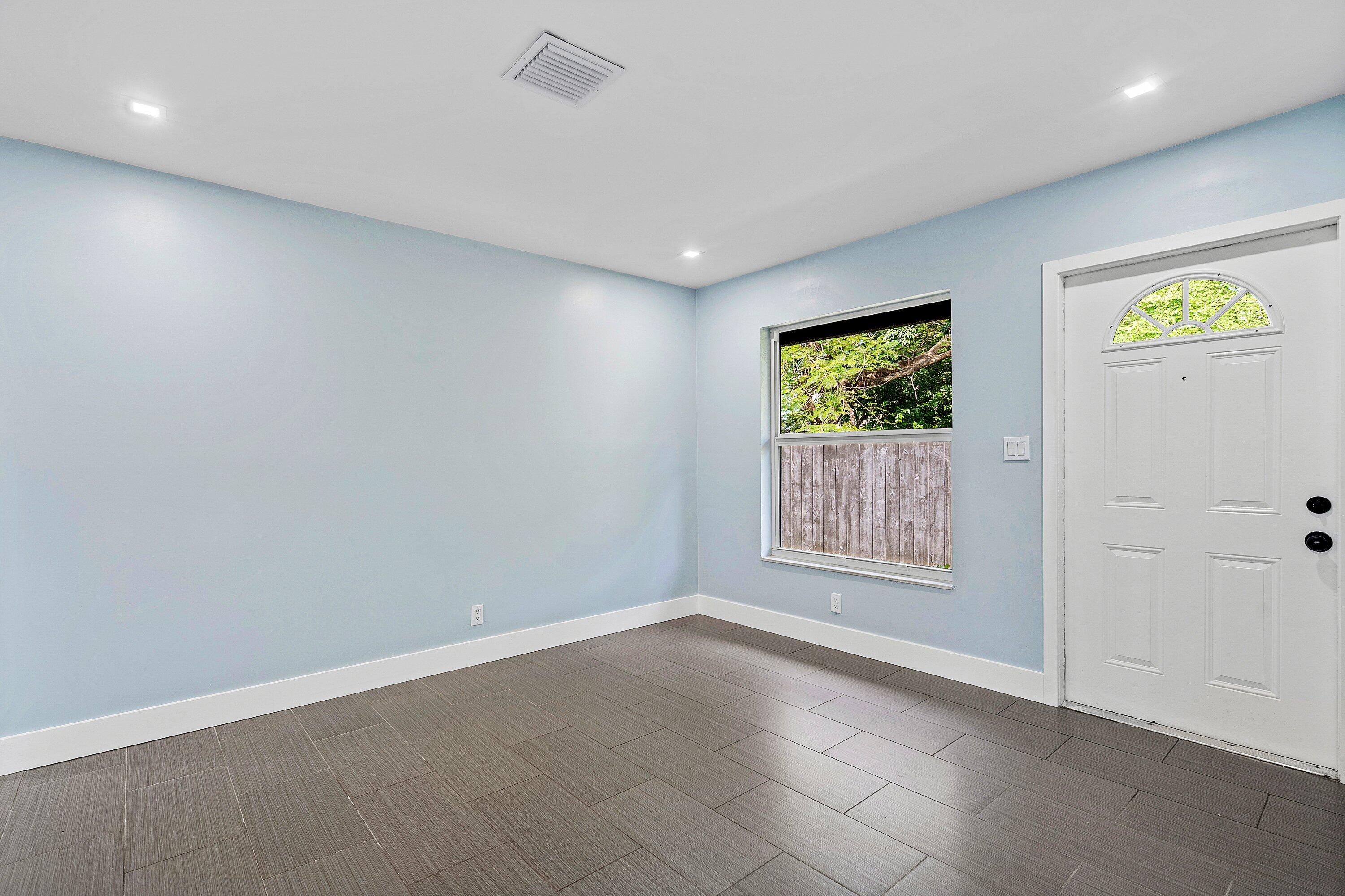 Room featuring neutral wall paint, tile flooring, recessed lighting, and a single-hung window with a metal-frame exterior door
