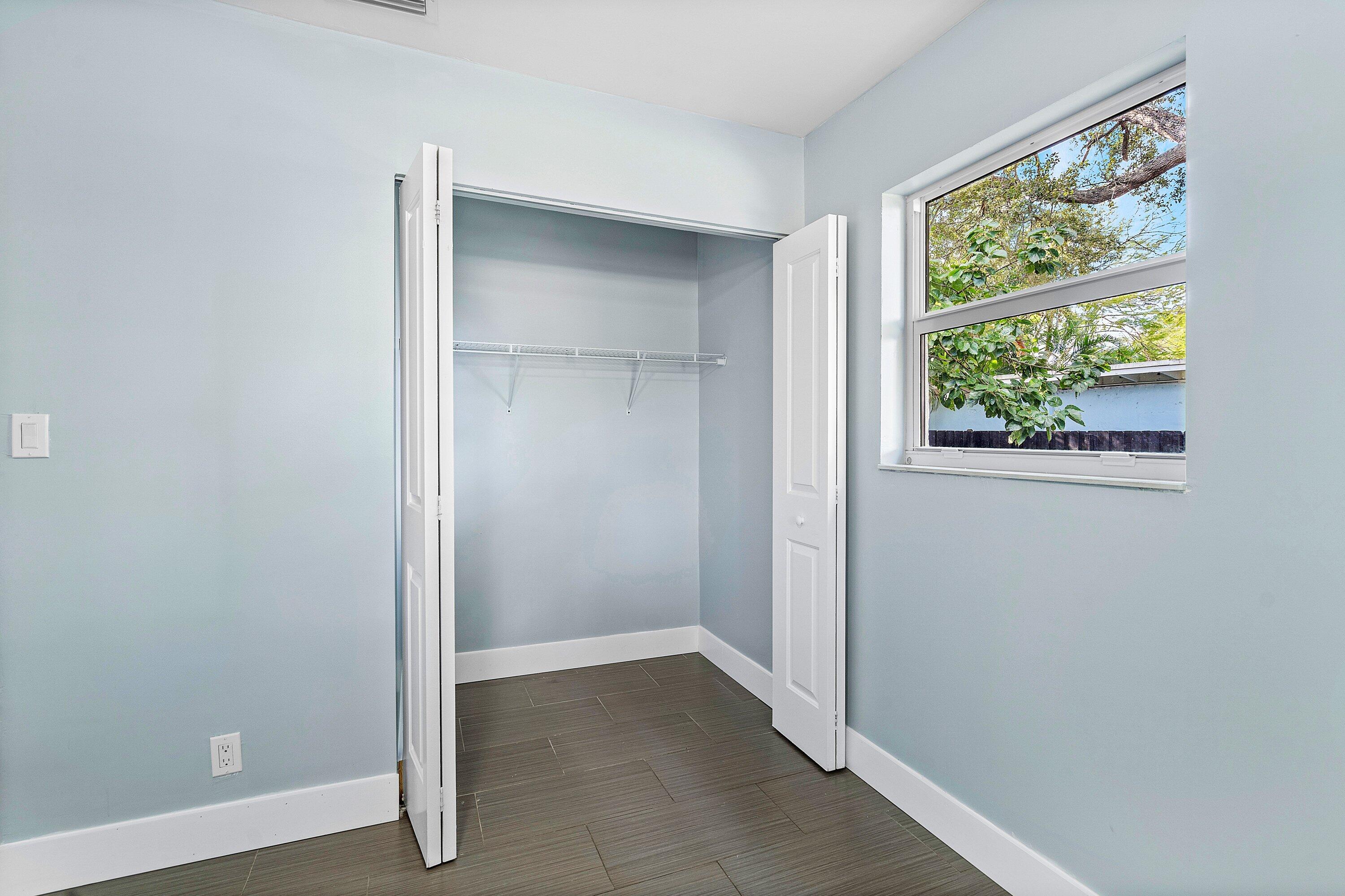 Neutral-toned room featuring a single-hung window, closet with bi-fold doors and wire shelving, and tile flooring