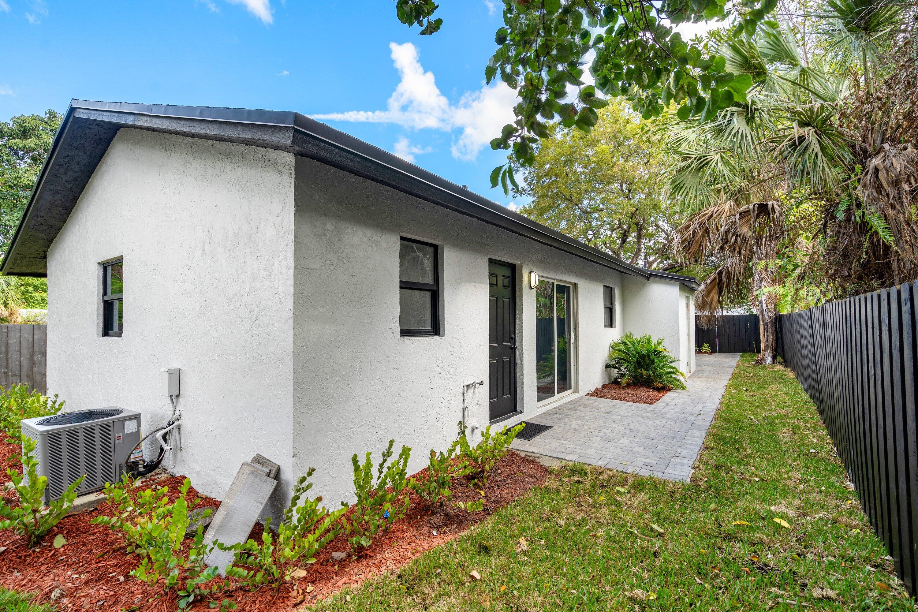 Stucco exterior featuring a paver patio, sliding glass door, and dark-toned privacy fencing