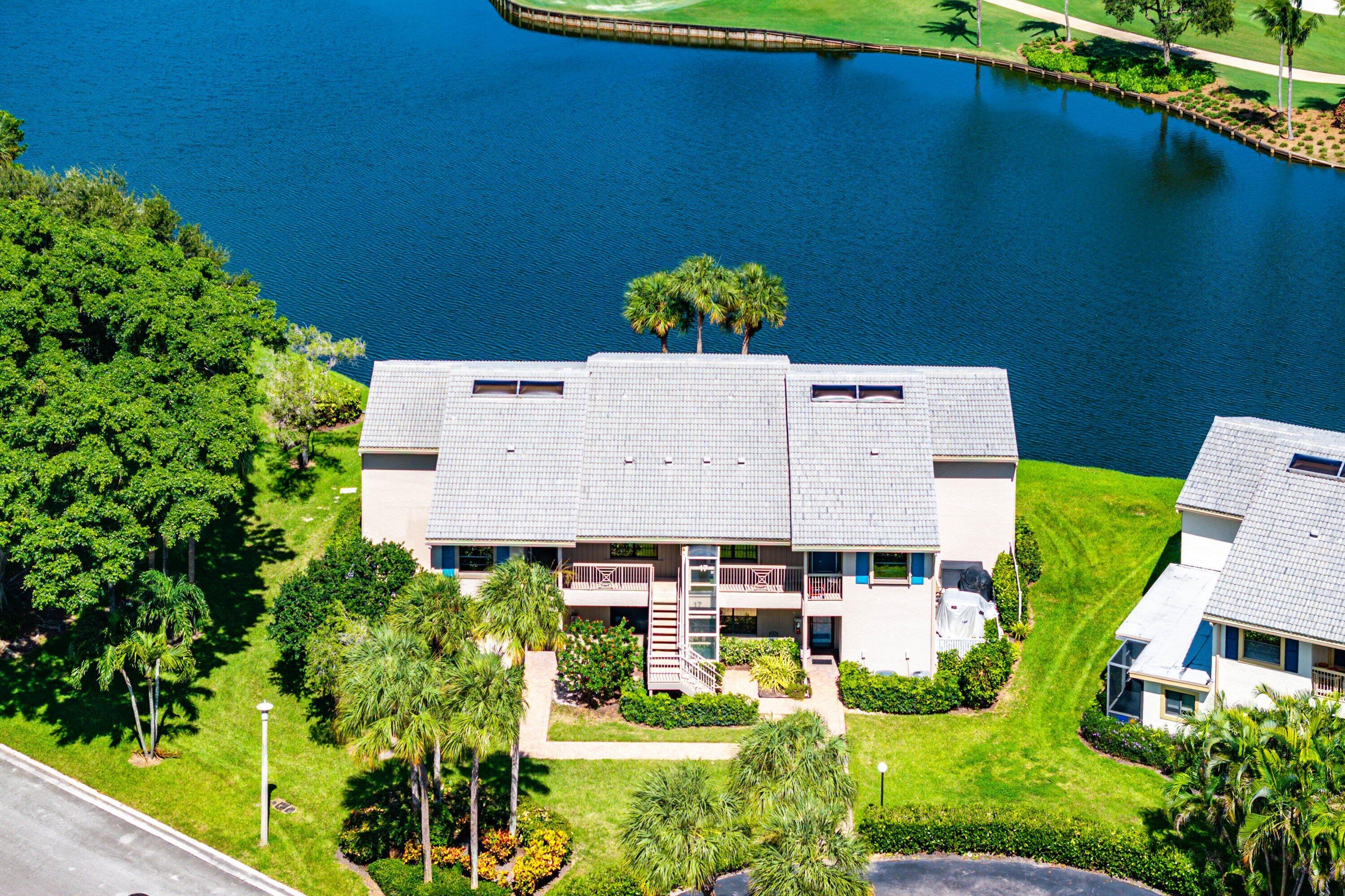 Multi-level building exterior featuring light-toned masonry, shingled roofing, balcony spaces, and waterfront positioning