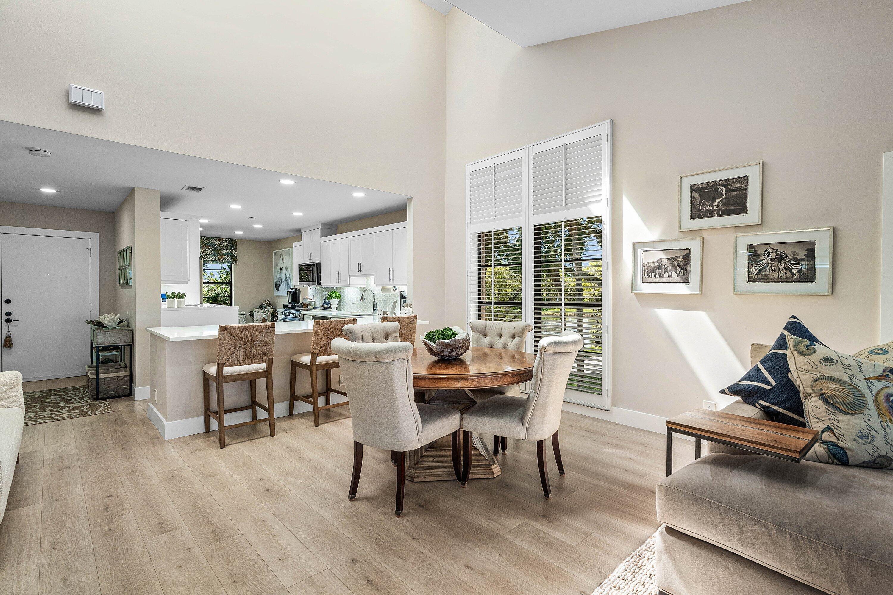 Open-concept space featuring vaulted ceilings, wood-finish flooring, recessed lighting, and a kitchen island with stone-finish countertops Open-concept space featuring vaulted ceilings, wood-finish flooring, recessed lighting, and a kitchen island with stone-finish countertops