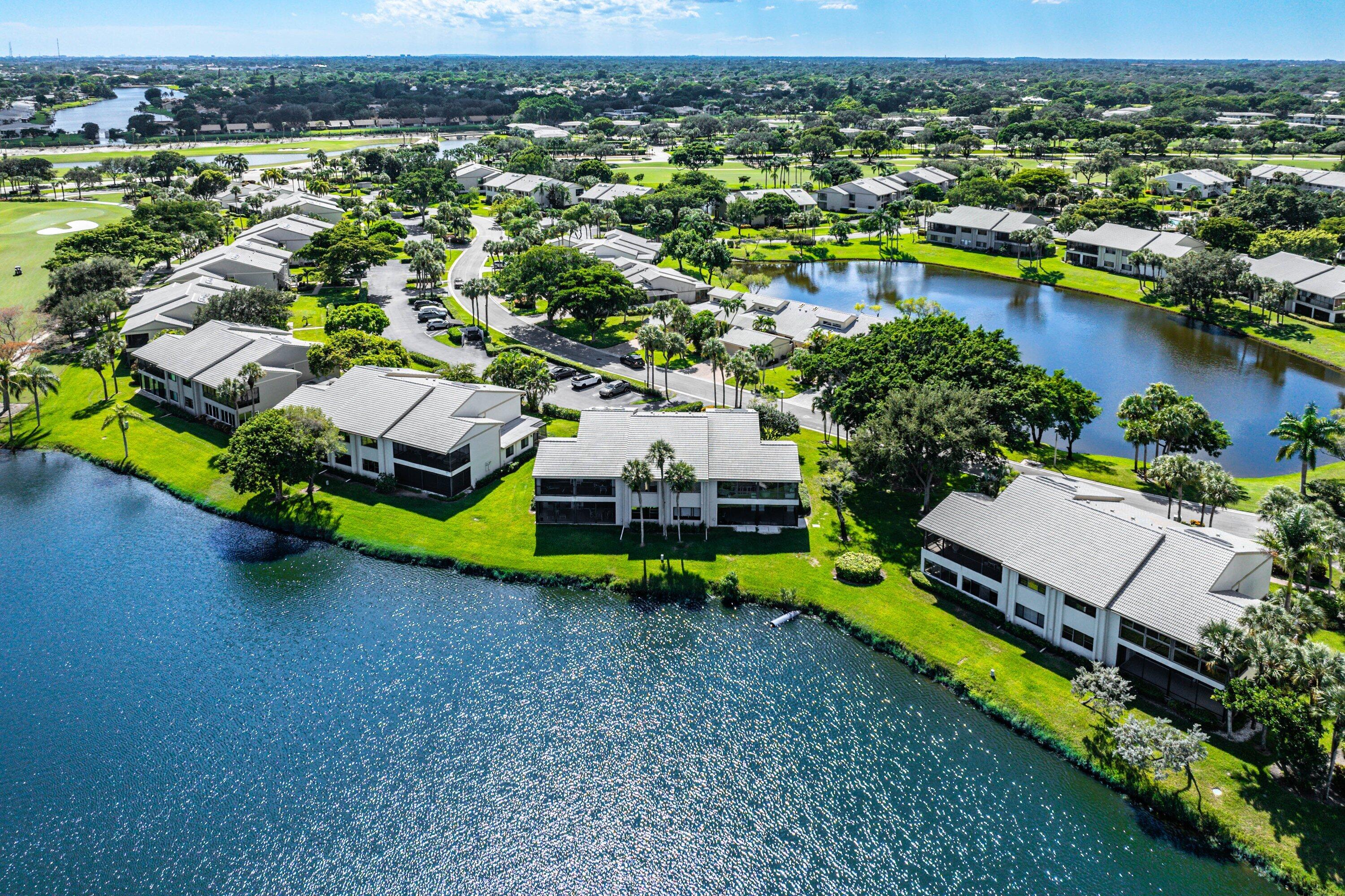 Aerial perspective of multi-unit residential buildings situated along a water feature with expansive green space and mature landscaping