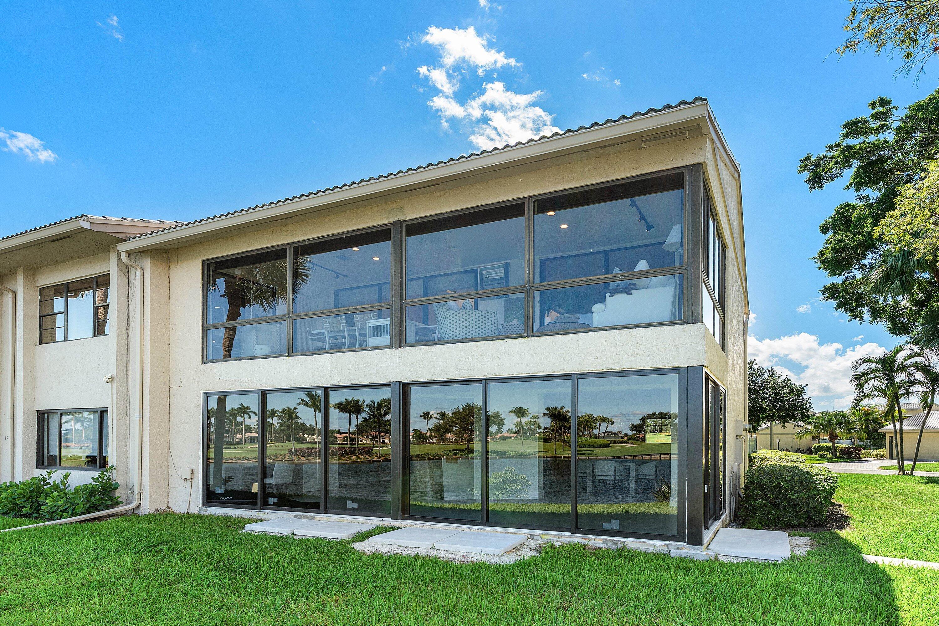 Two-story stucco exterior featuring floor-to-ceiling glass paneling and dual-level enclosed lanais