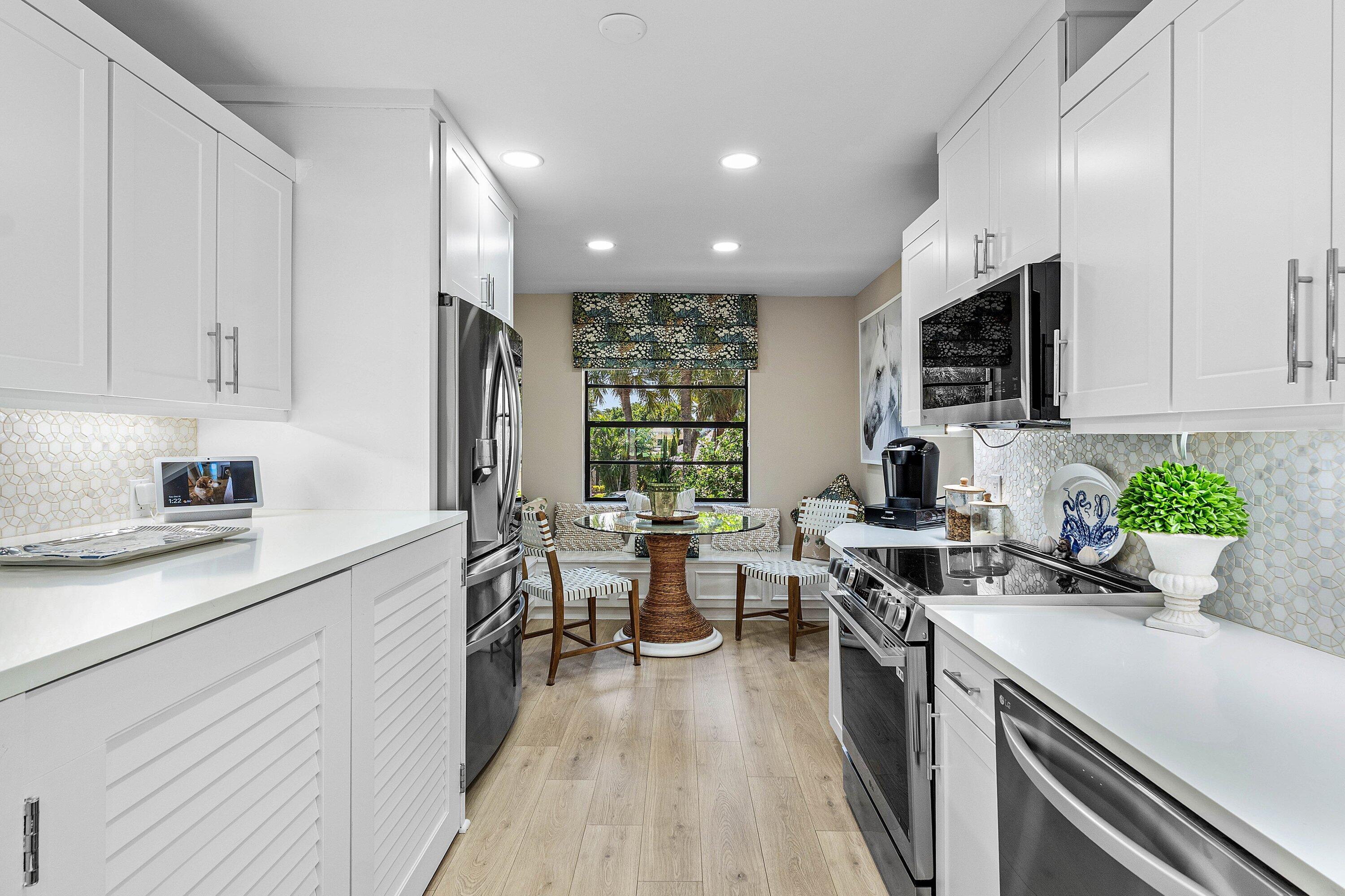 Kitchen featuring white shaker-style cabinetry, solid-surface countertops, patterned tile backsplash, stainless steel appliances, and wood-finish flooring