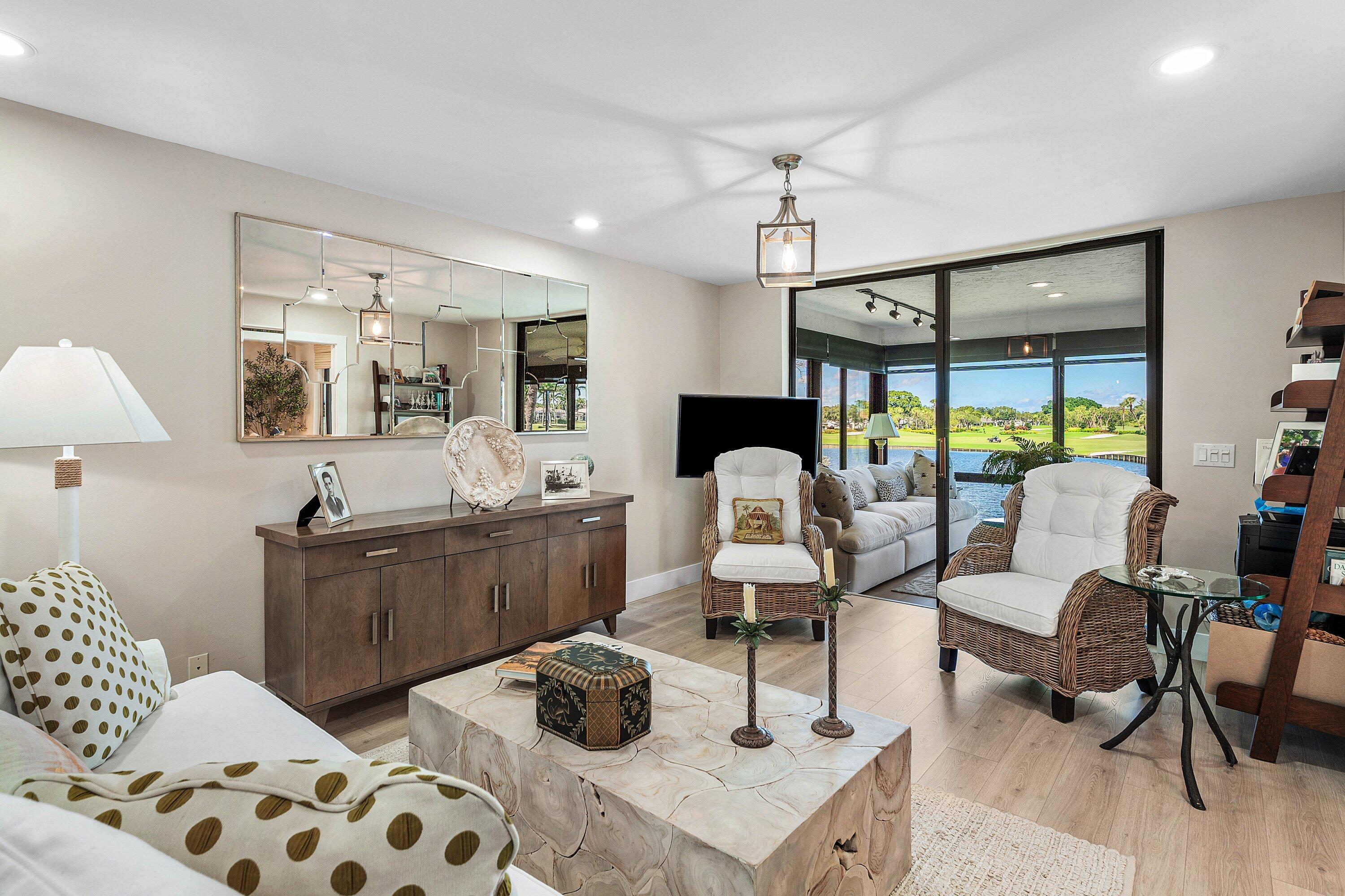 Living area featuring wood-finish flooring, recessed lighting, a large-scale wall mirror, and sliding glass doors opening to a screened enclosure