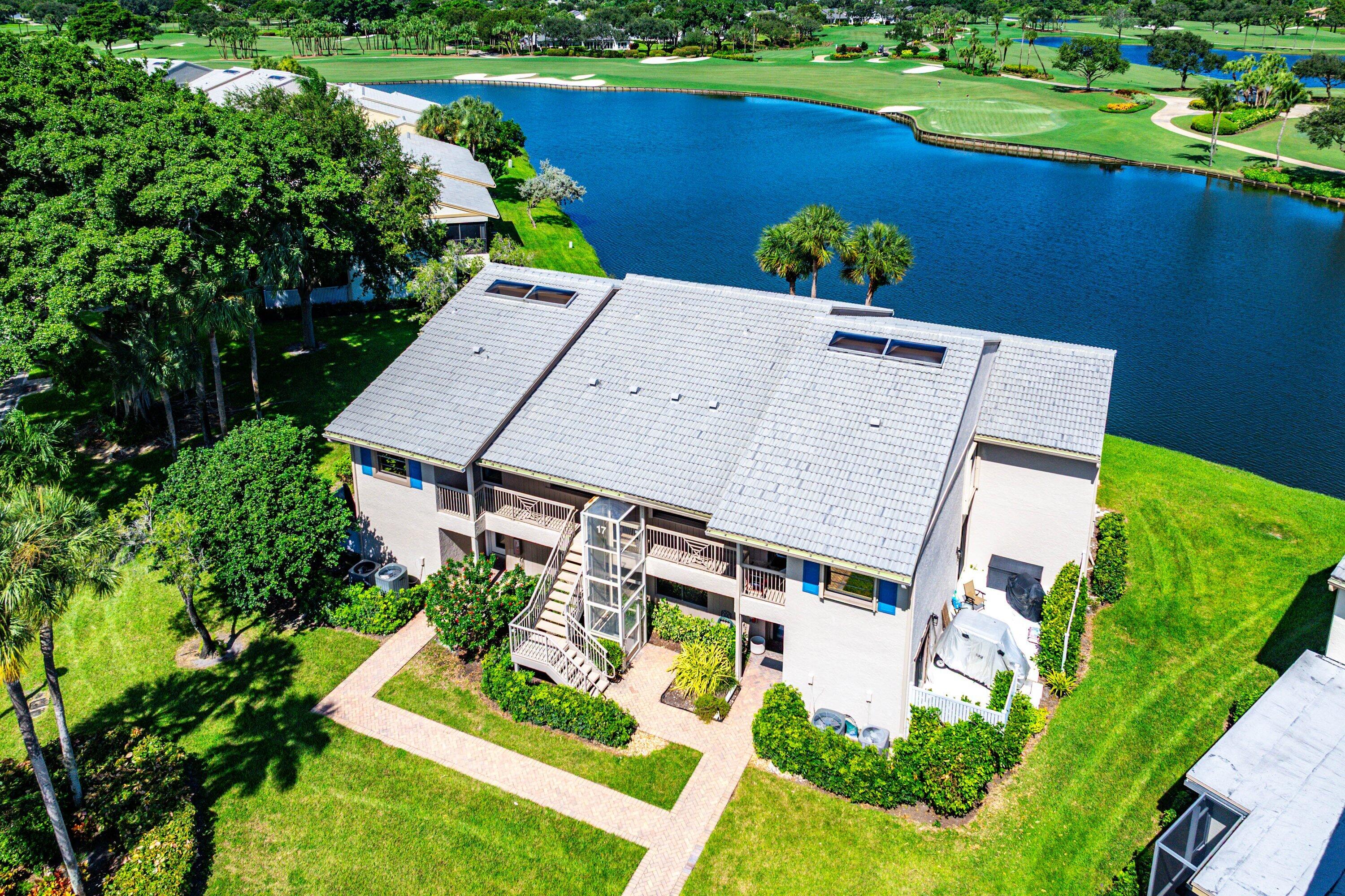 Multi-story building featuring a tile roof, built-in skylights, exterior staircase, and paved walkways situated on a waterfront lot