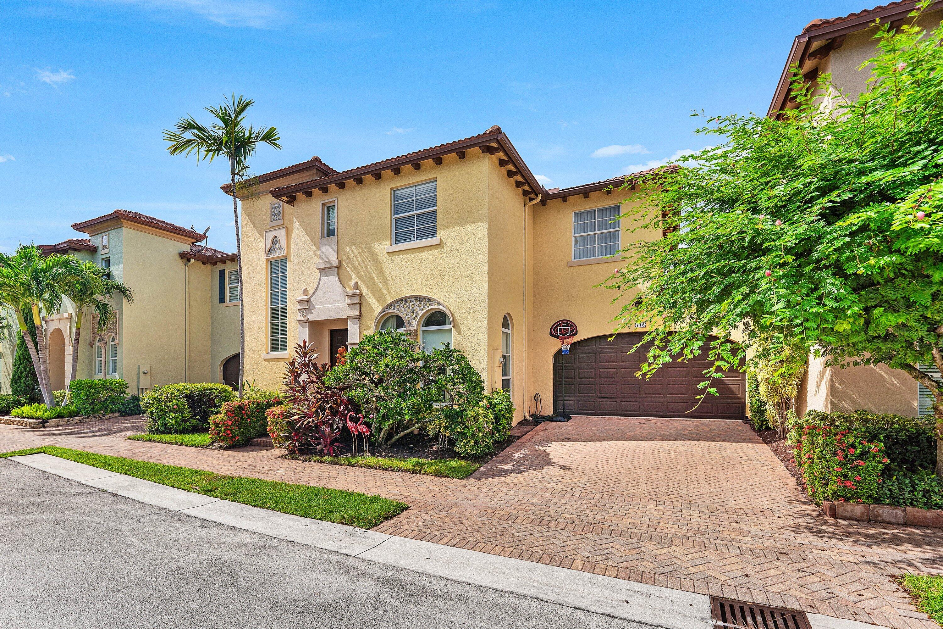 Inviting exterior view highlighting the well-maintained landscaping, arched details, and private two-car garage