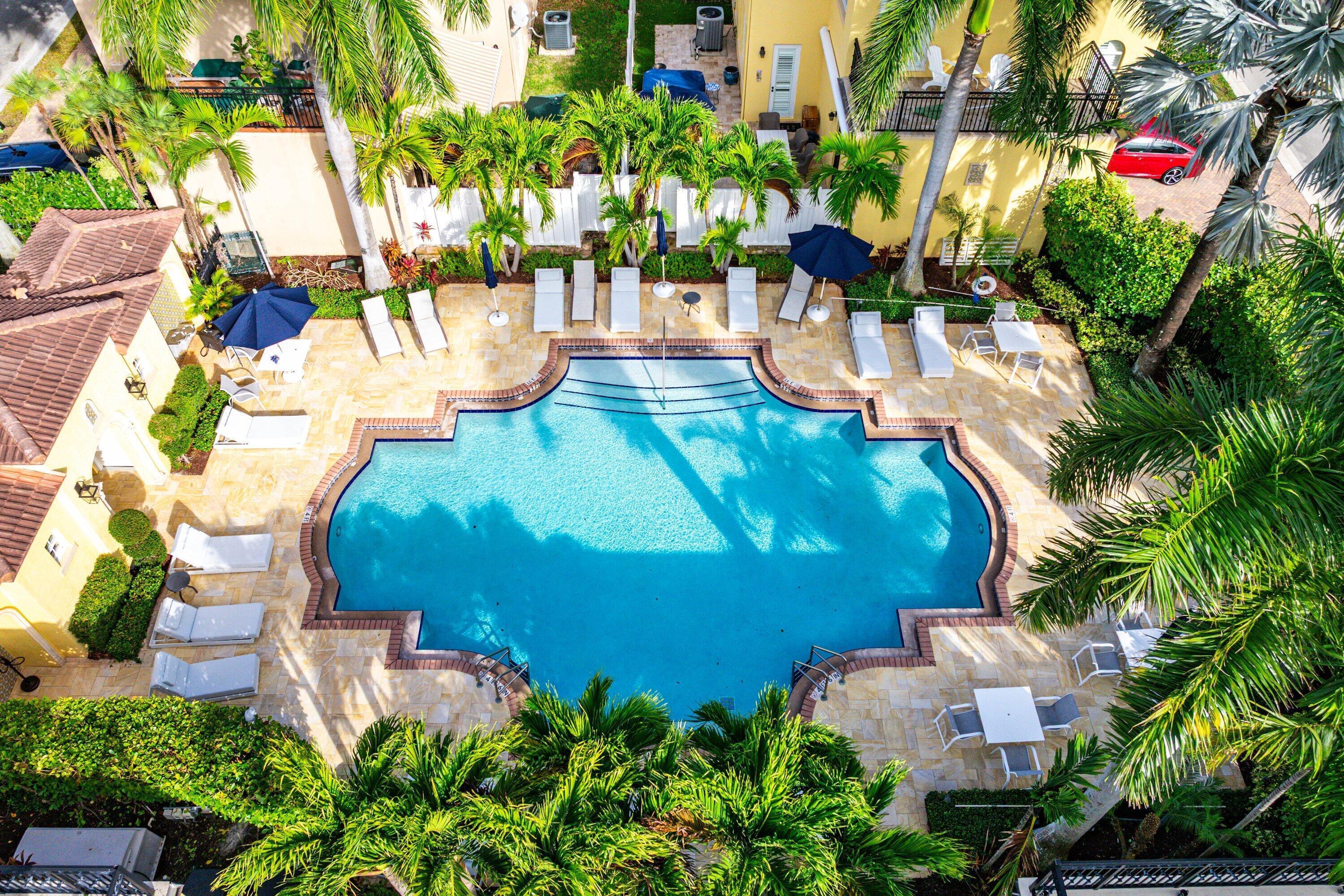 Beautiful community pool with tropical landscaping and lounge area.