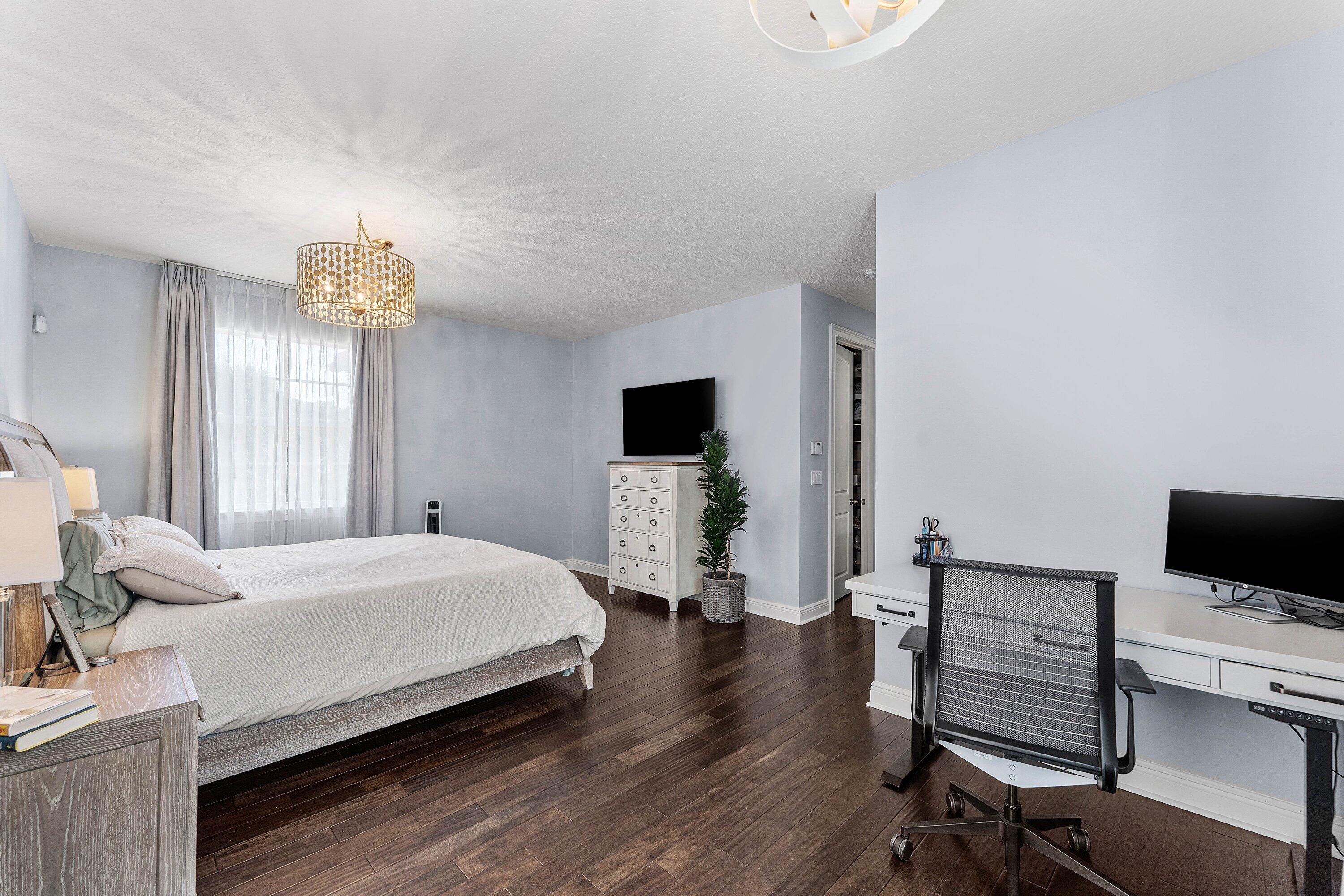 Bright master bedroom featuring wood flooring, modern furnishings, generous space, and large windows with beautiful natural light.