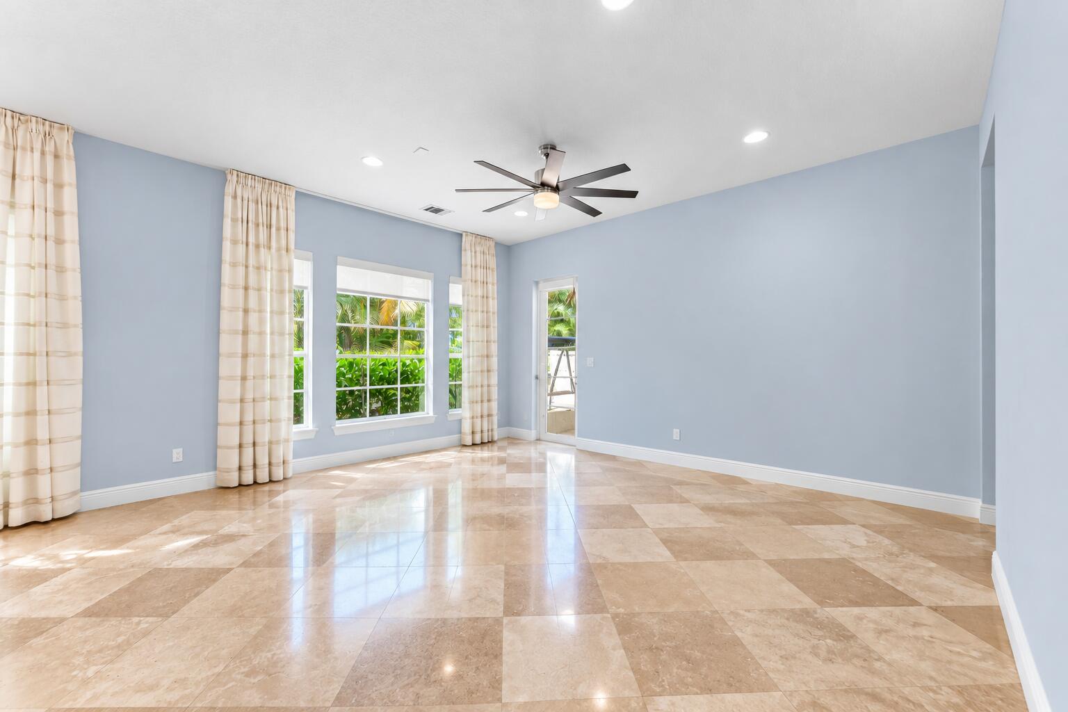 Bright, spacious family room featuring polished tile floors, abundant natural light, recessed lighting, and seamless access to the outdoor living space.