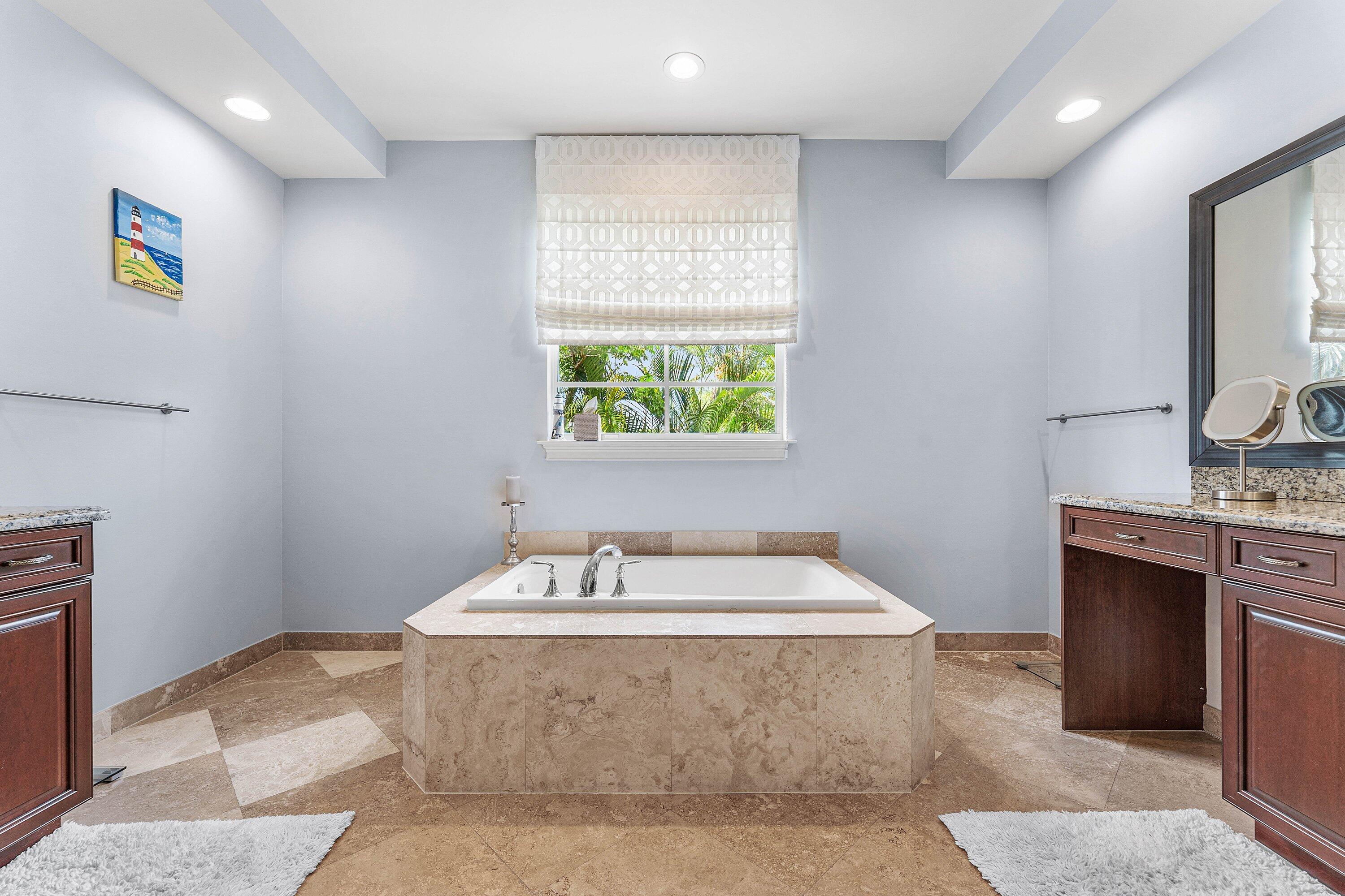 Spacious master bathroom featuring a large garden tub, dual sinks, granite countertops, and abundant natural light.