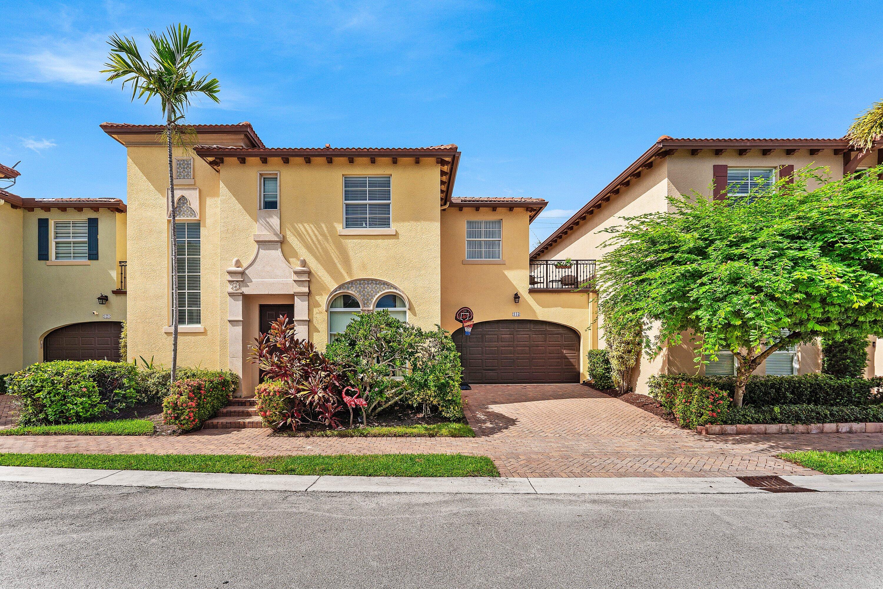 Beautiful front exterior showcasing the homes elegant Mediterranean-style architecture, lush landscaping, and spacious driveway