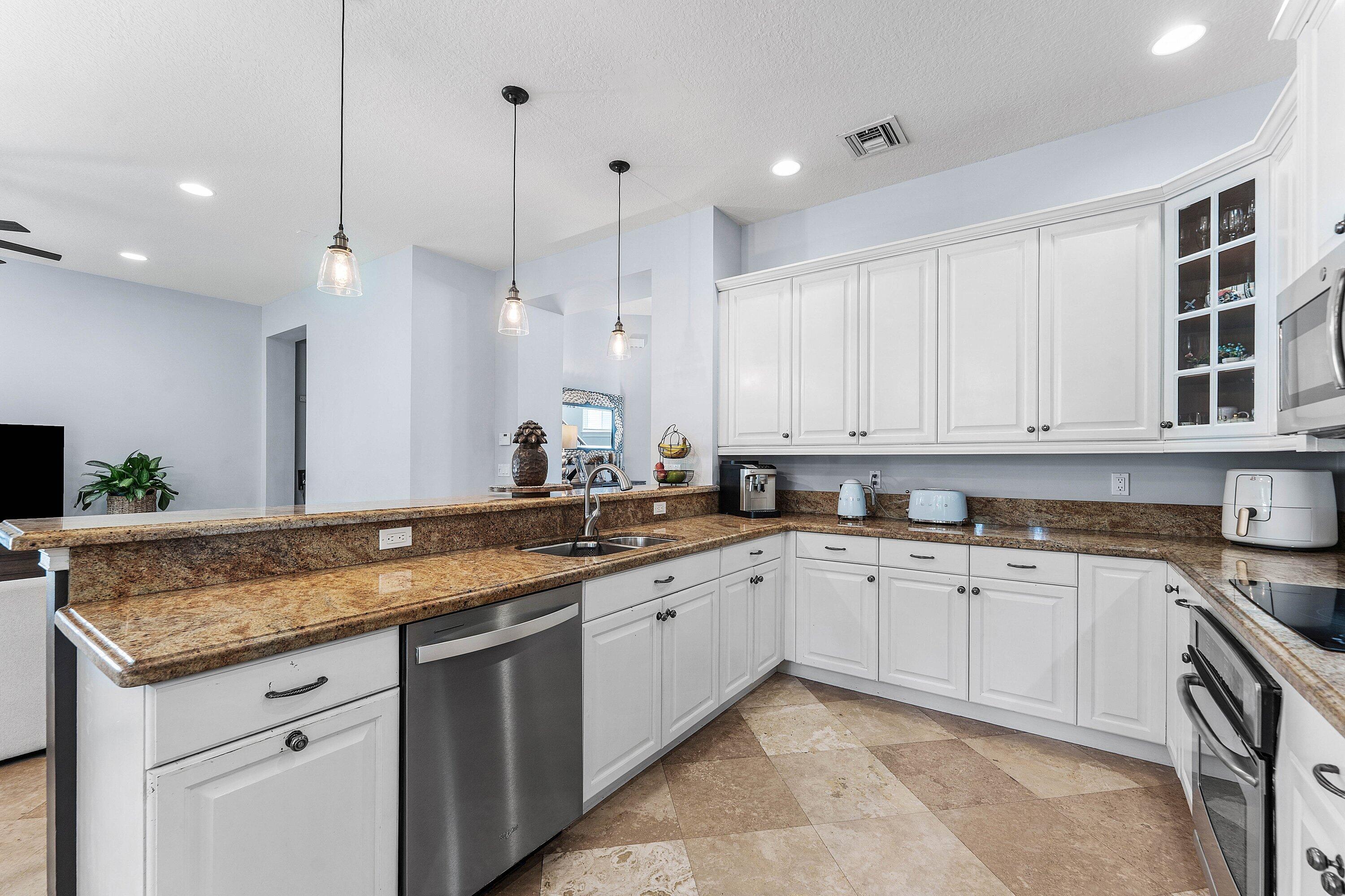 Beautiful modern kitchen showcasing white cabinets, granite countertops, stainless steel appliances, custom glass-front cabinetry, and ample counter space.
