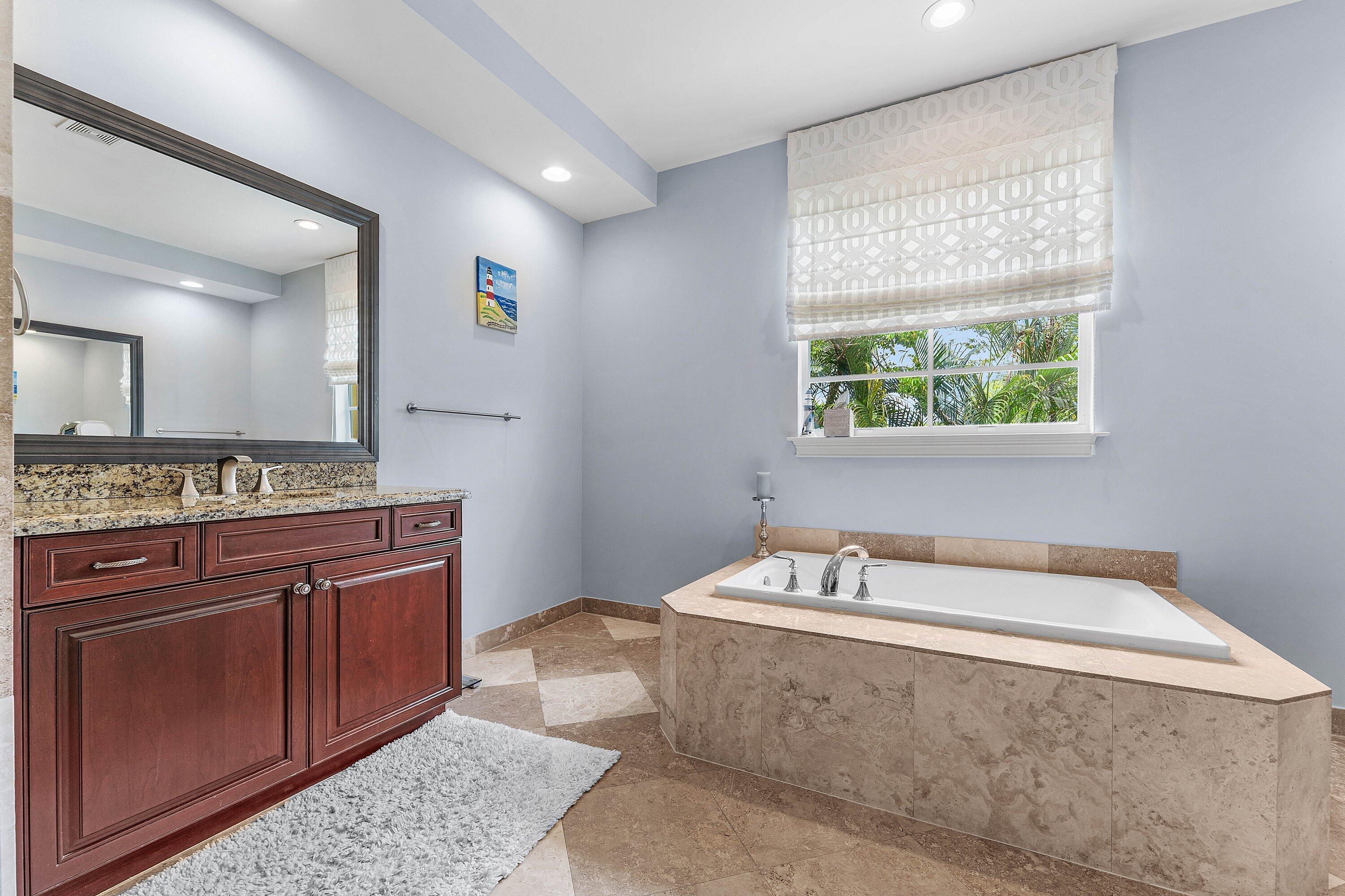 Luxurious master bathroom with a large soaking tub, dual vanities, granite countertops, and a bright, spa-like atmosphere.