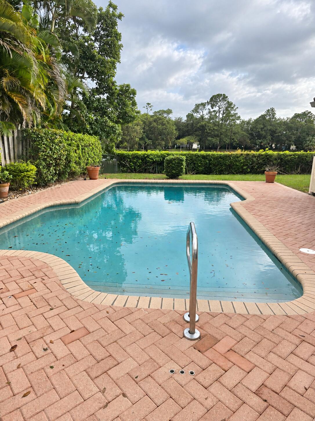 Inviting Outdoor Pool with Expansive Brick Paver Patio & Lush Tropical Landscaping