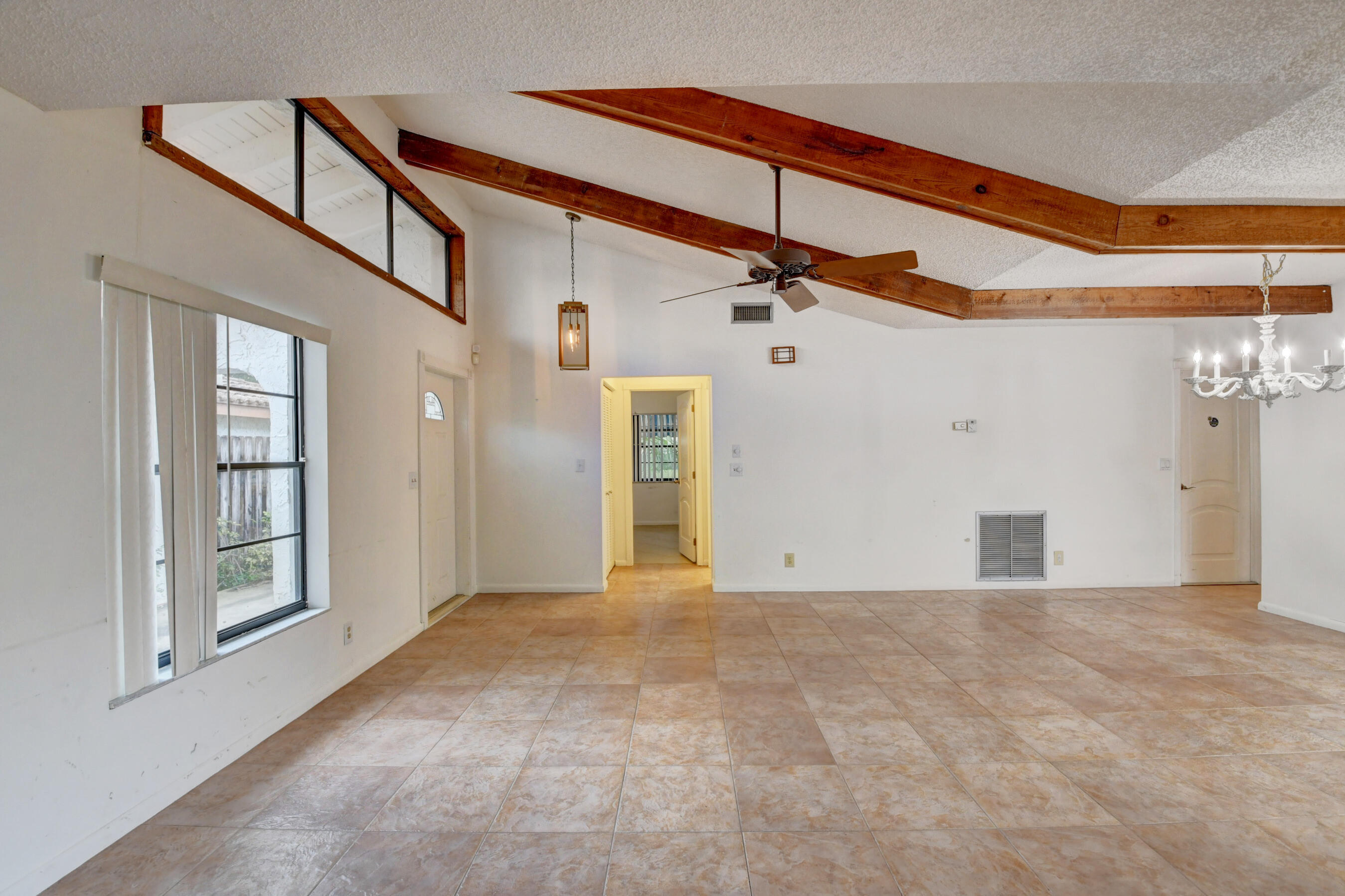 Expansive Living Area with Exposed Wood Beams, Tile Flooring & Abundant Natural Light
