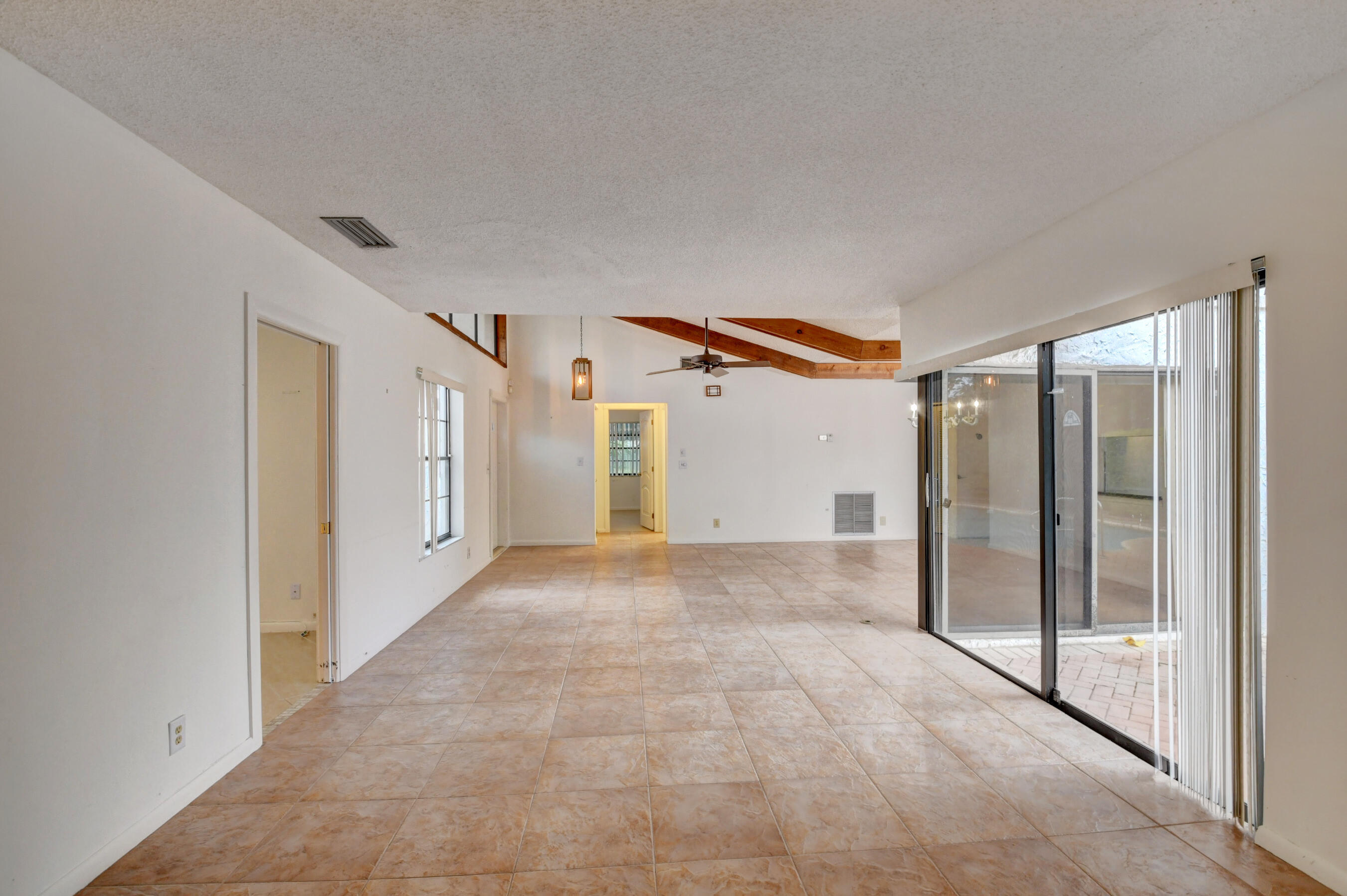 Expansive Living Area with Exposed Wood Beams, Tile Flooring & Abundant Natural Light