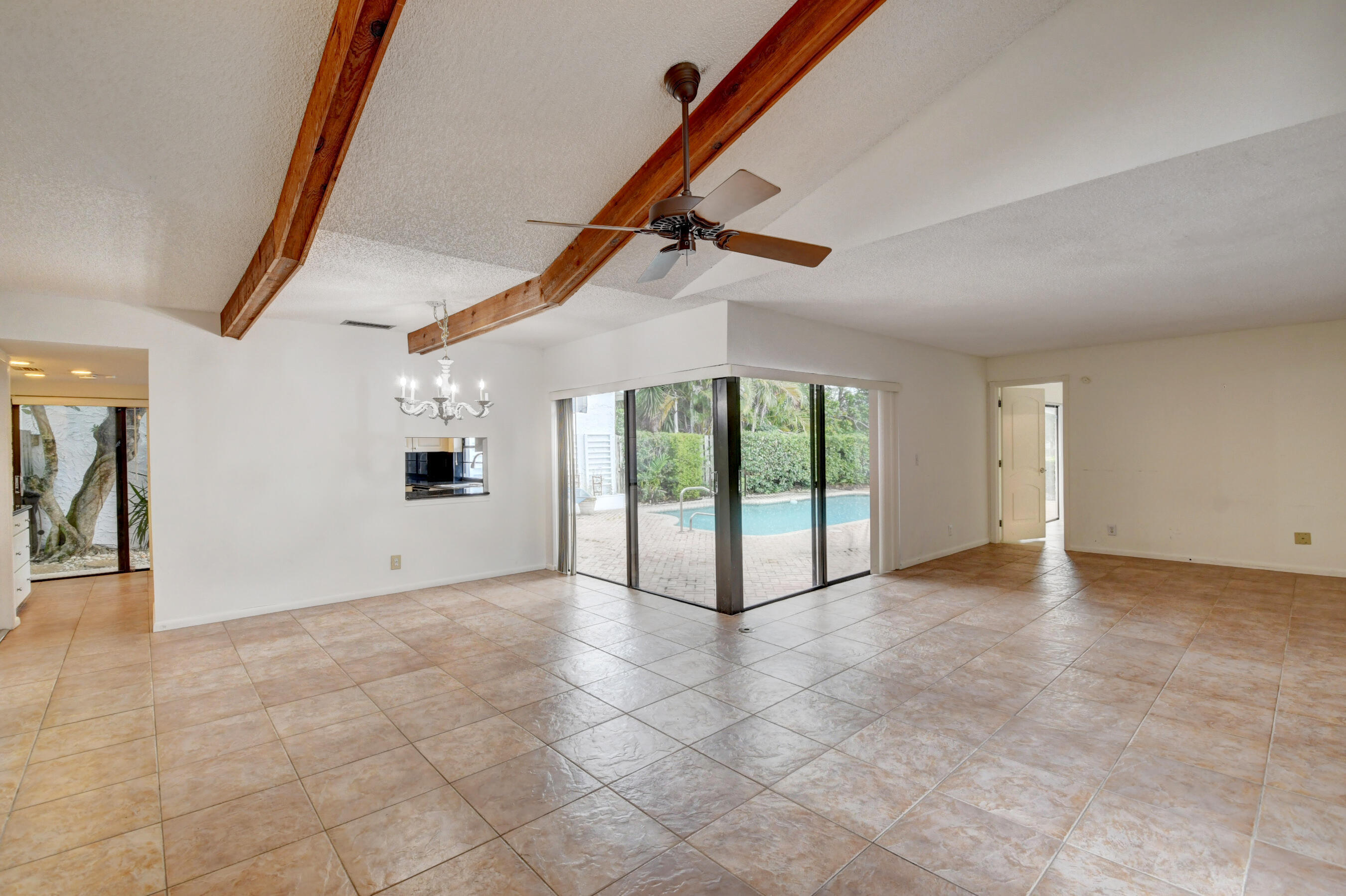 Expansive Living Area with Exposed Wood Beams, Tile Flooring & Abundant Natural Light