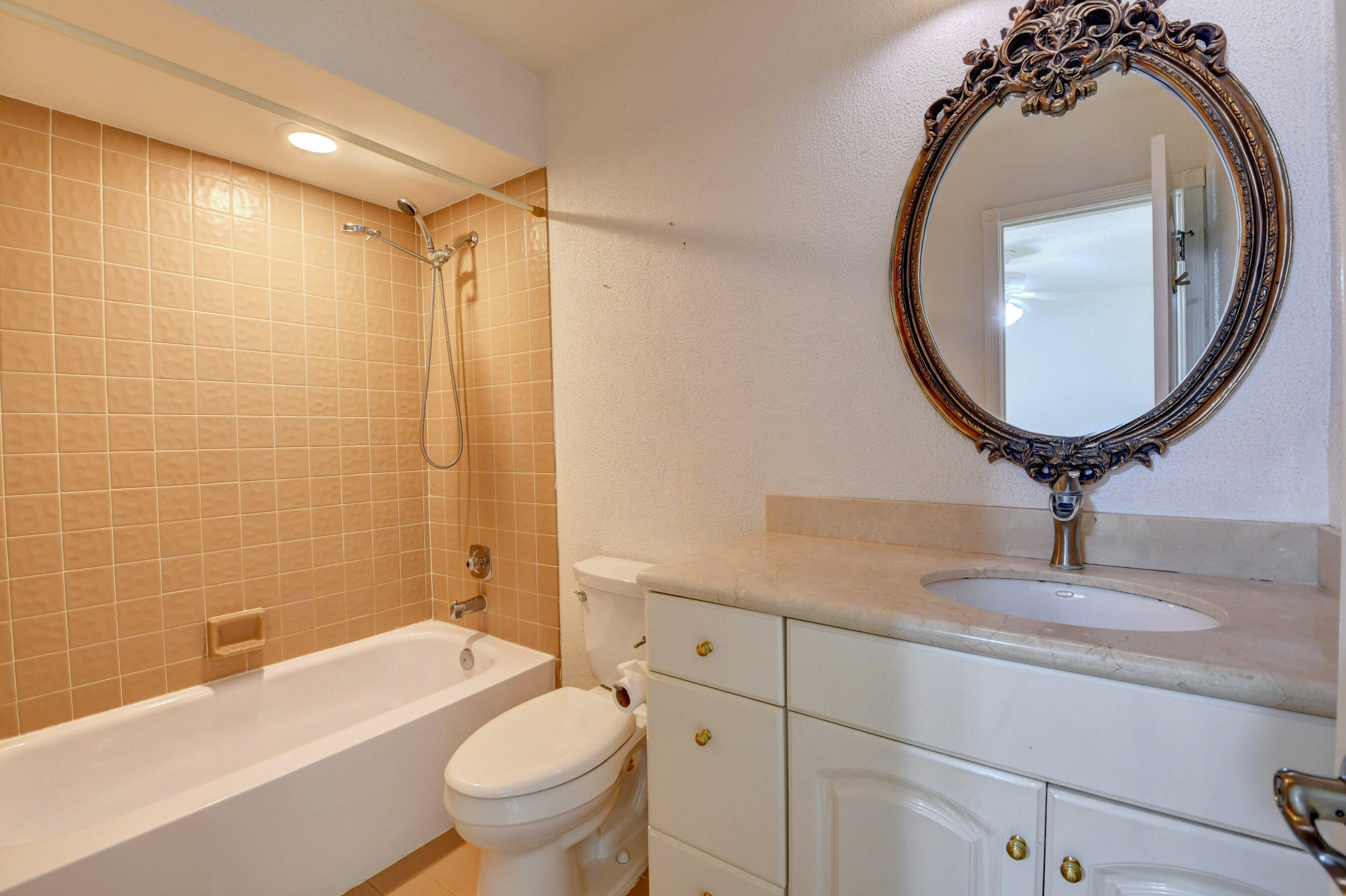 Spacious Guest Bathroom with Tiled Bathtub, Classic Vanity & Decorative Mirror