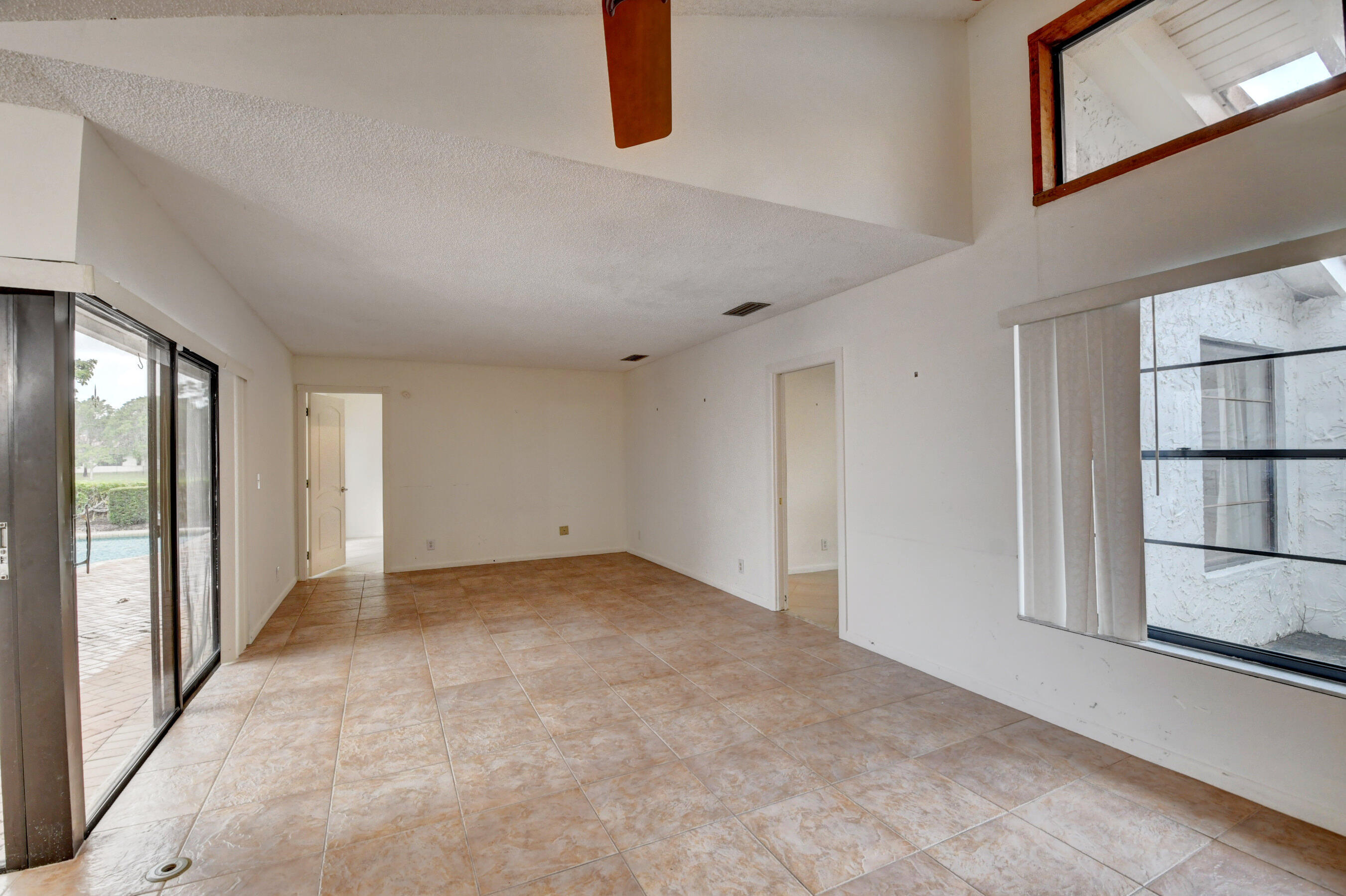 Expansive Living Area with Exposed Wood Beams, Tile Flooring & Abundant Natural Light