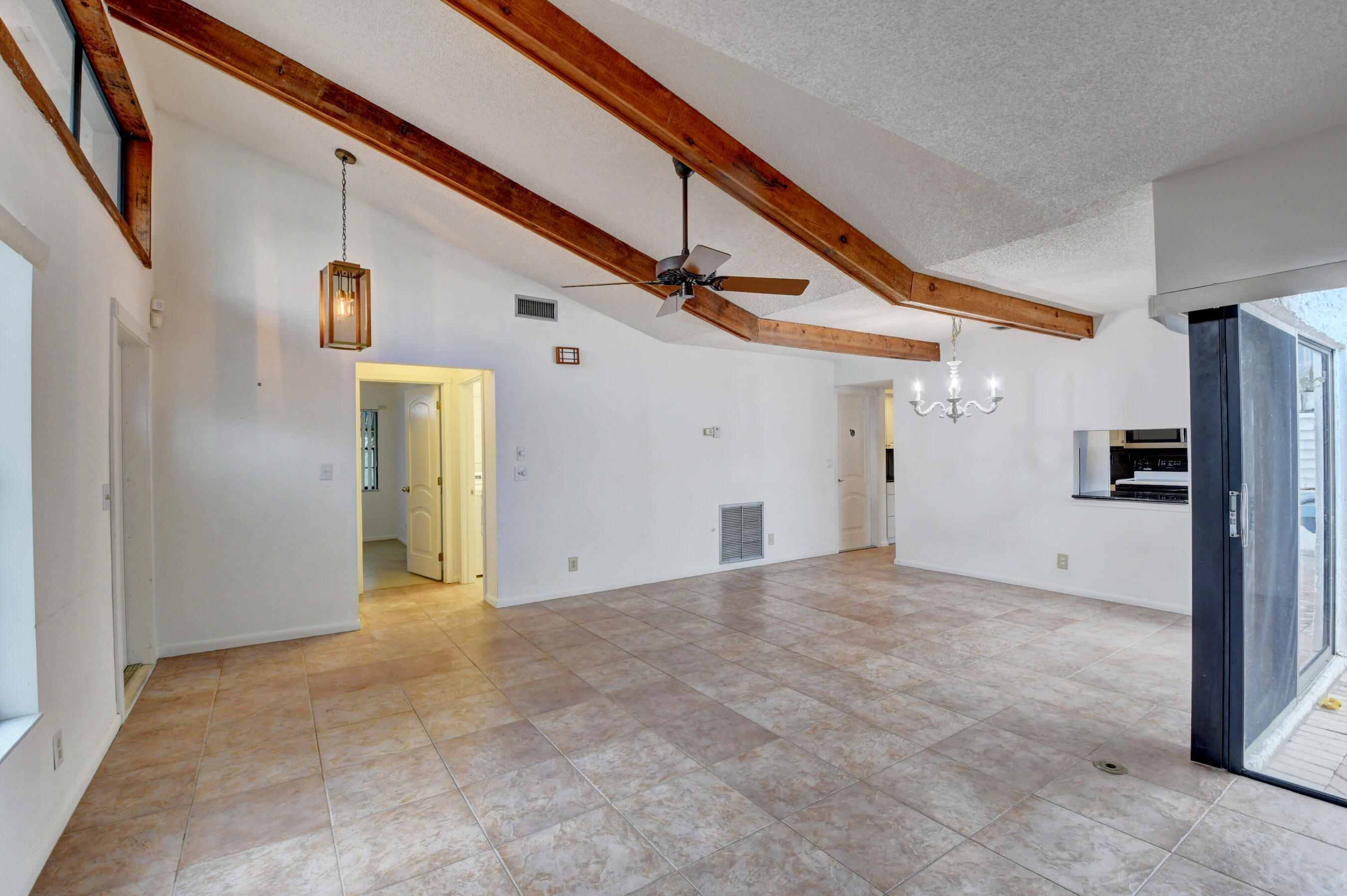 Expansive Living Area with Exposed Wood Beams, Tile Flooring & Abundant Natural Light