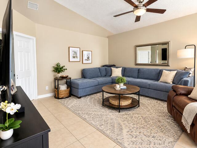 Welcoming living room offering vaulted ceilings, continuous ceramic tile flooring, ceiling fan, and an open layout ideal for entertaining.
