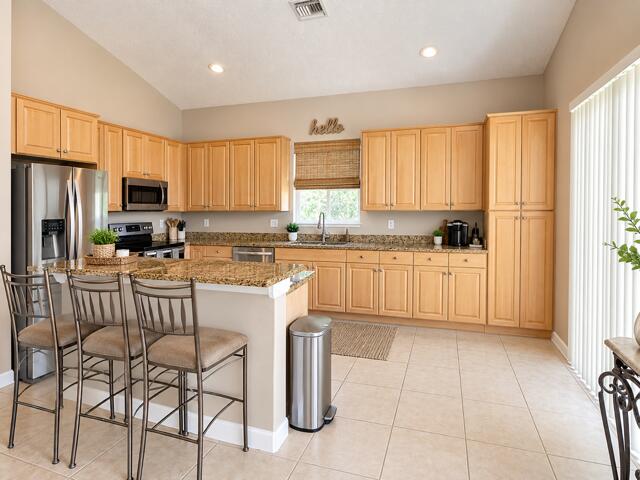 Spacious kitchen equipped with warm wood cabinetry, granite counter space, full-height pantry, stainless steel appliances, and multi-seat breakfast bar.
