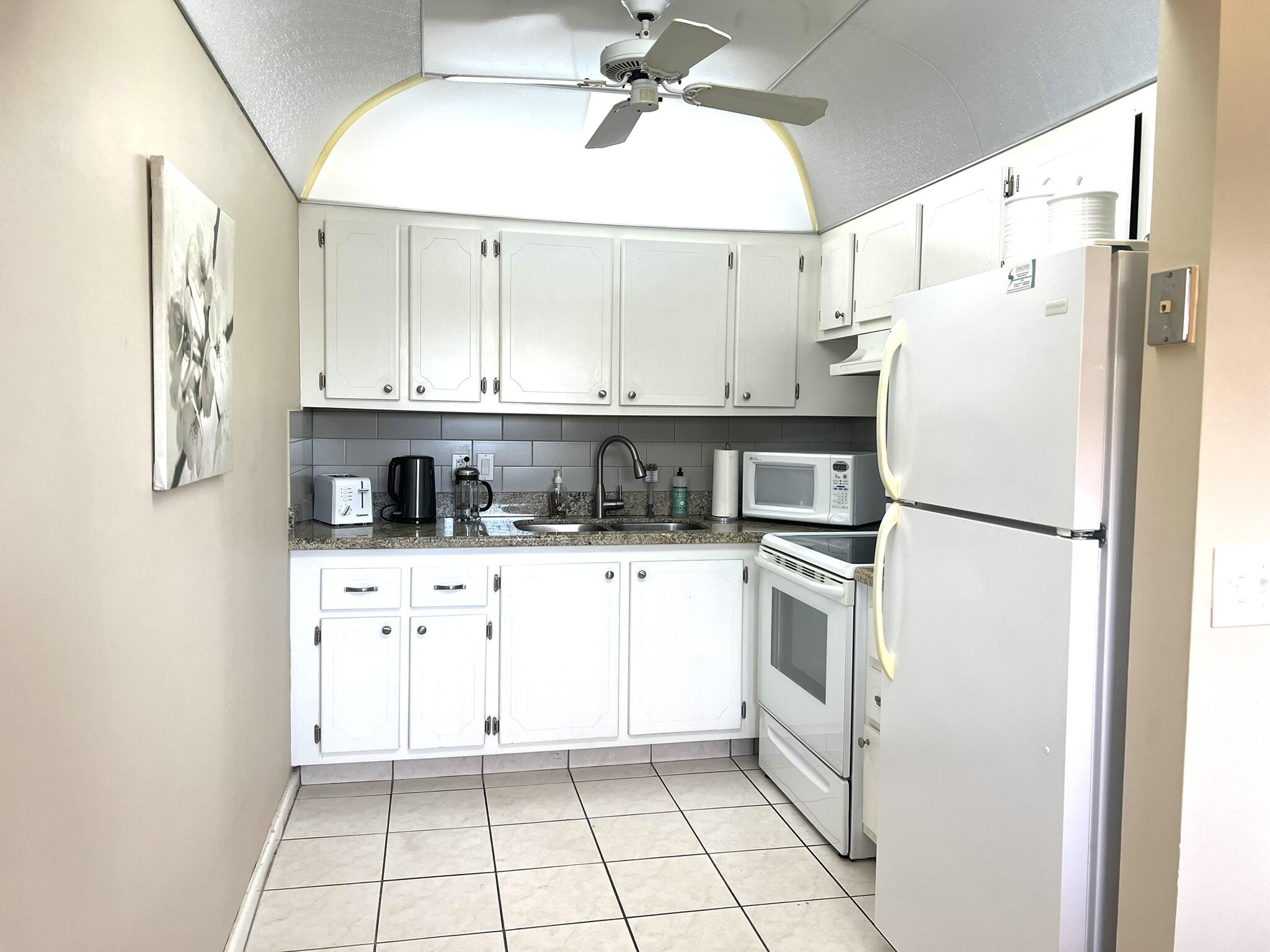 Kitchen with room for a prep cart or cabinet. Granite Countertops and subway backsplash