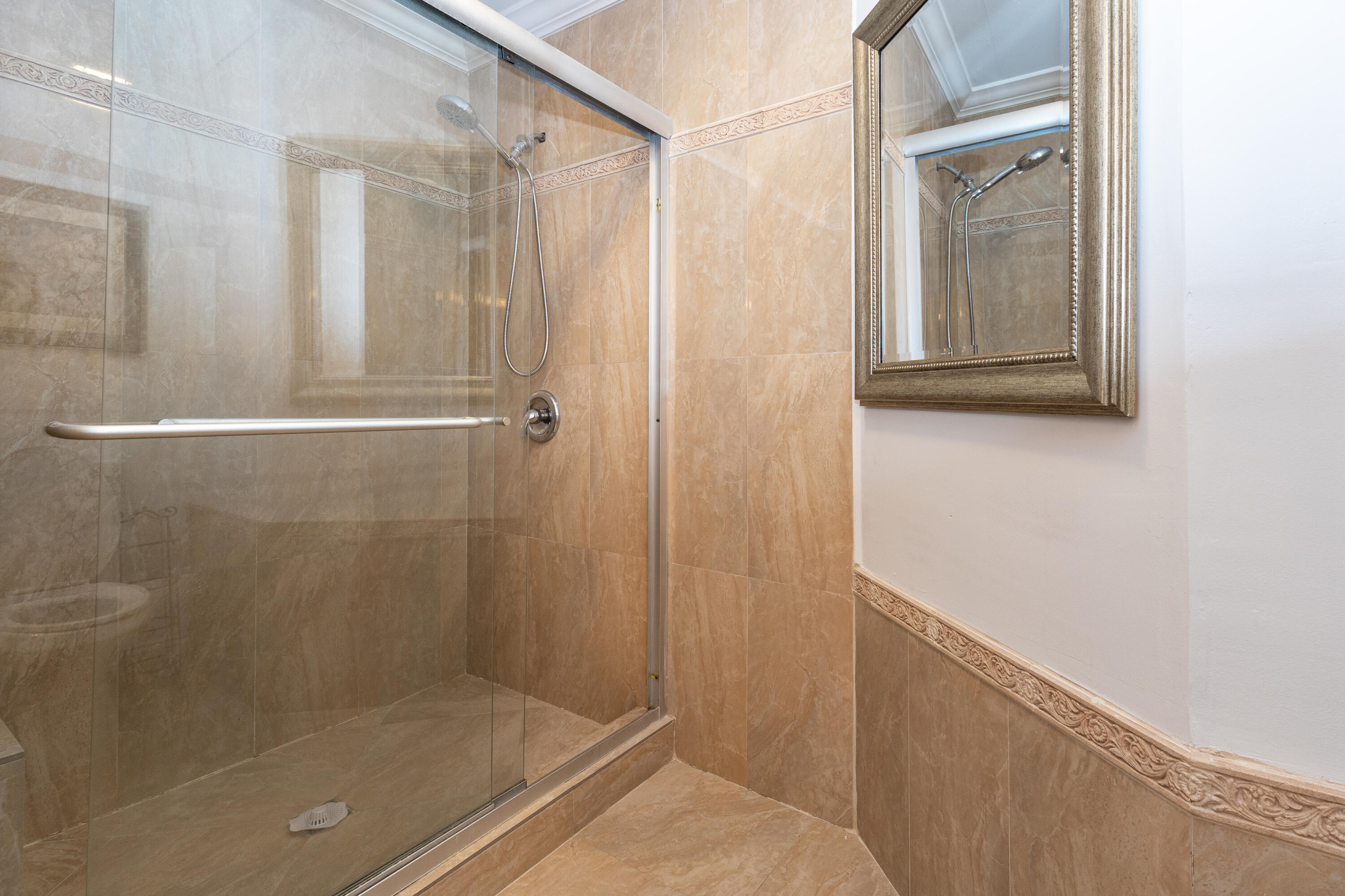 Spa-inspired shower featuring a frameless glass enclosure, wood-finish tile surround, and a linear floor drain