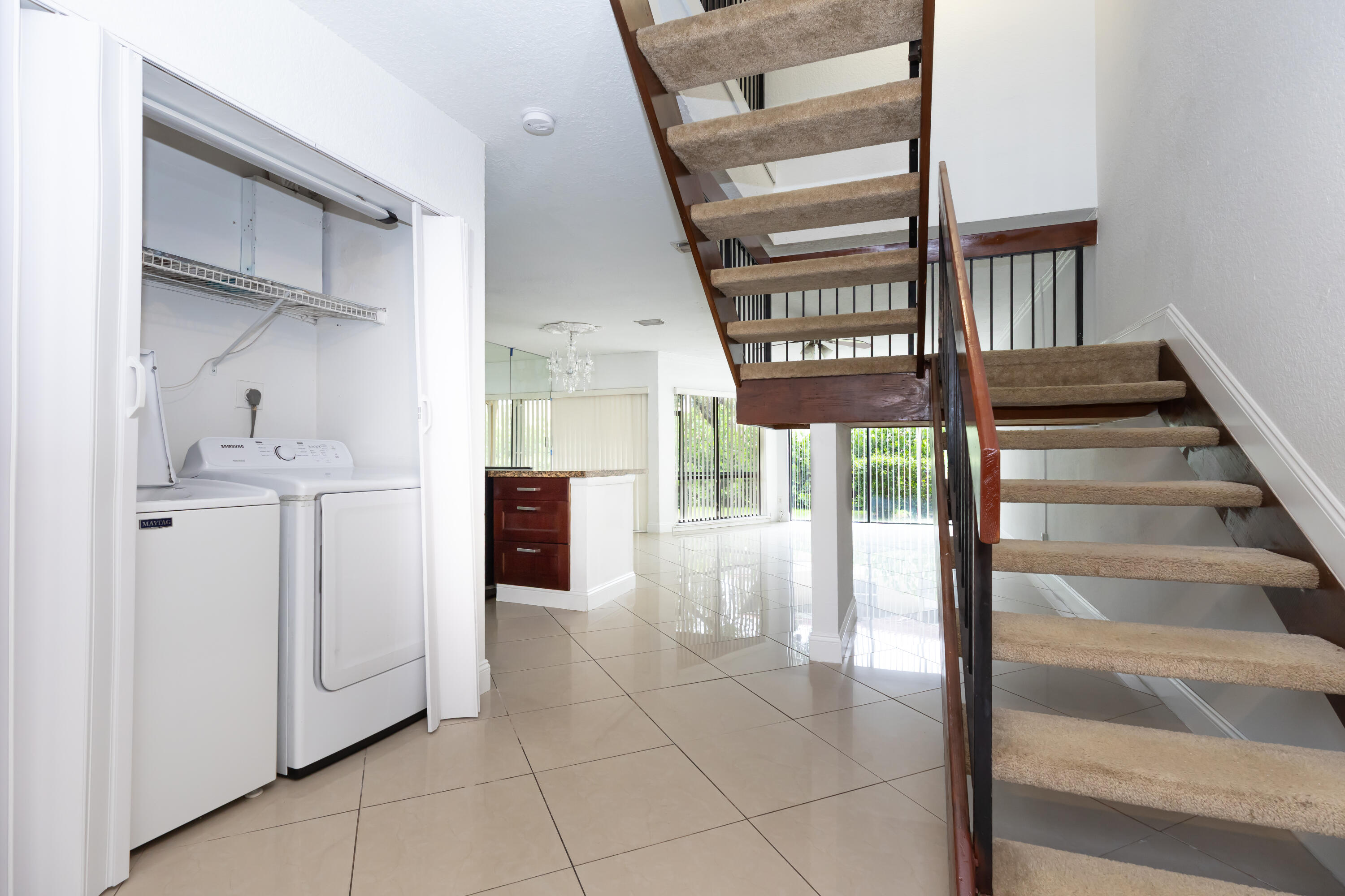 Built-in laundry closet, wood-finish staircase with carpeted treads, and tiled flooring throughout